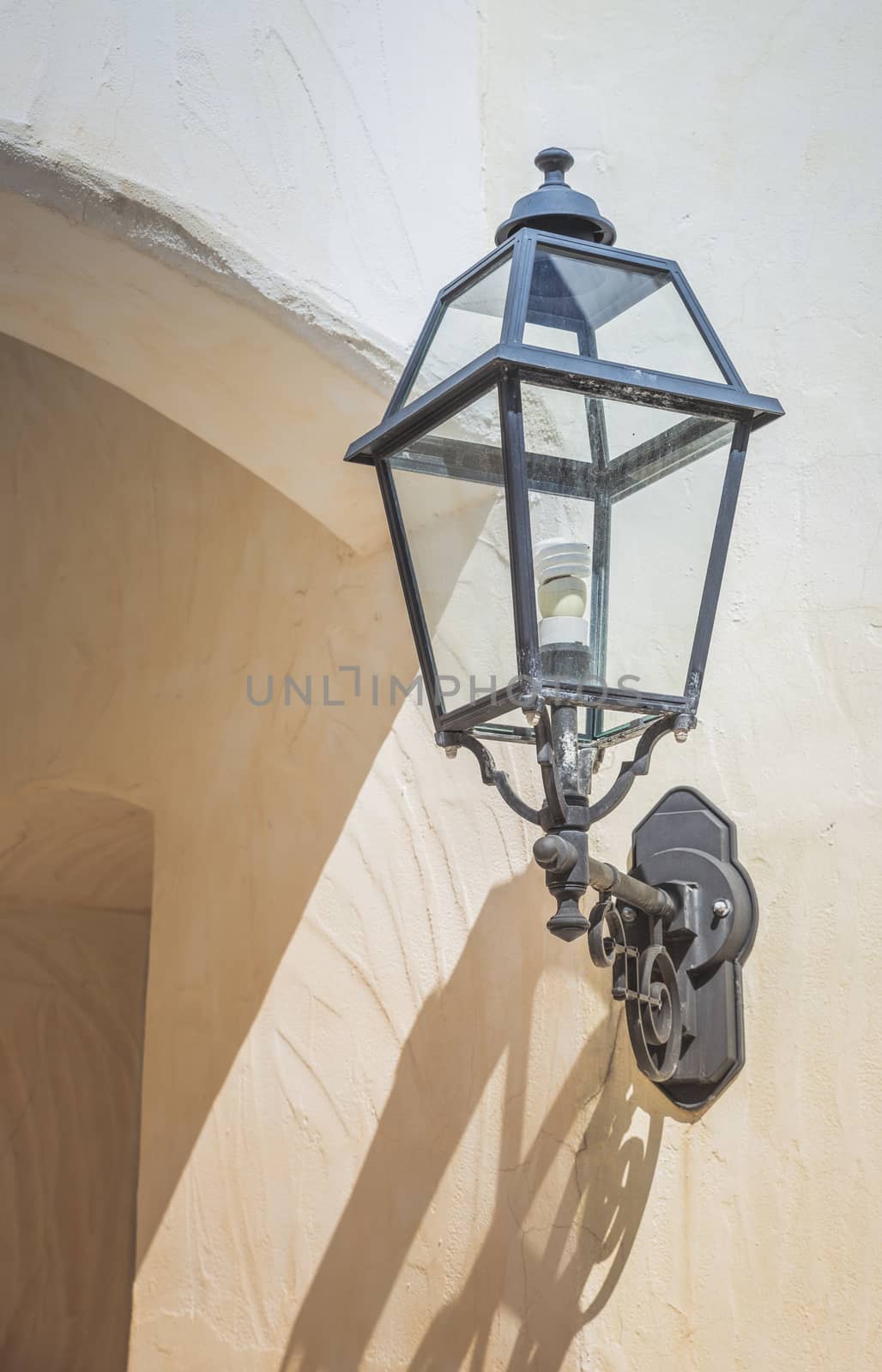 old vintage metal light with a modern led light inside against a white stone wall in sardinie