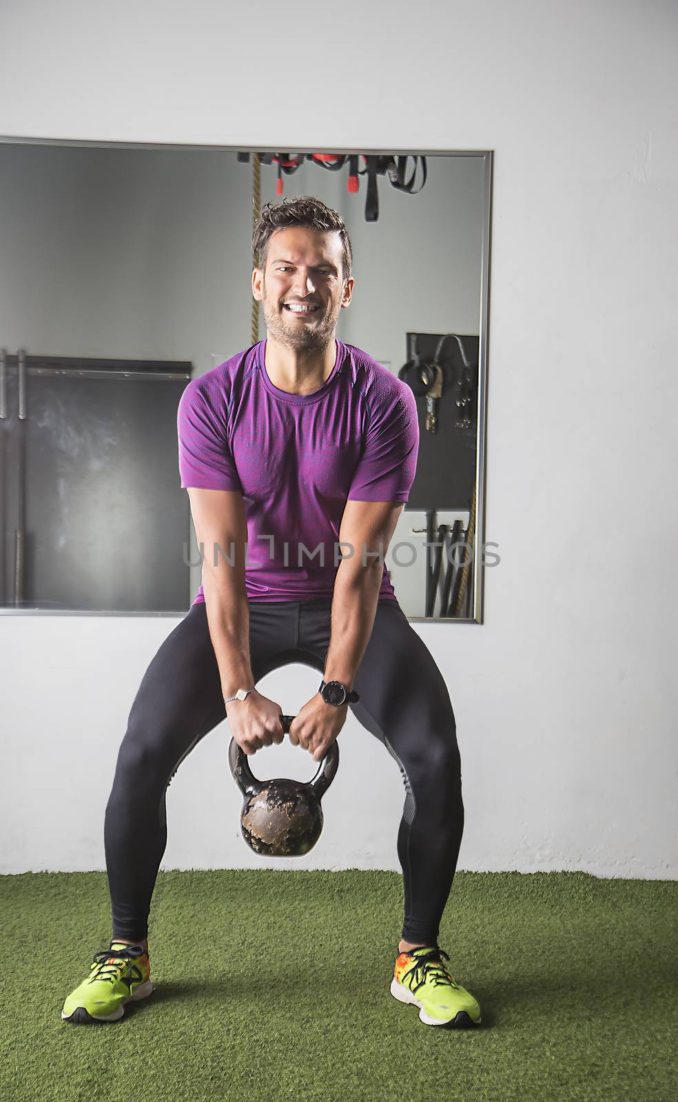 Young man in his thirties pulling on a scuffed metal kettle bell