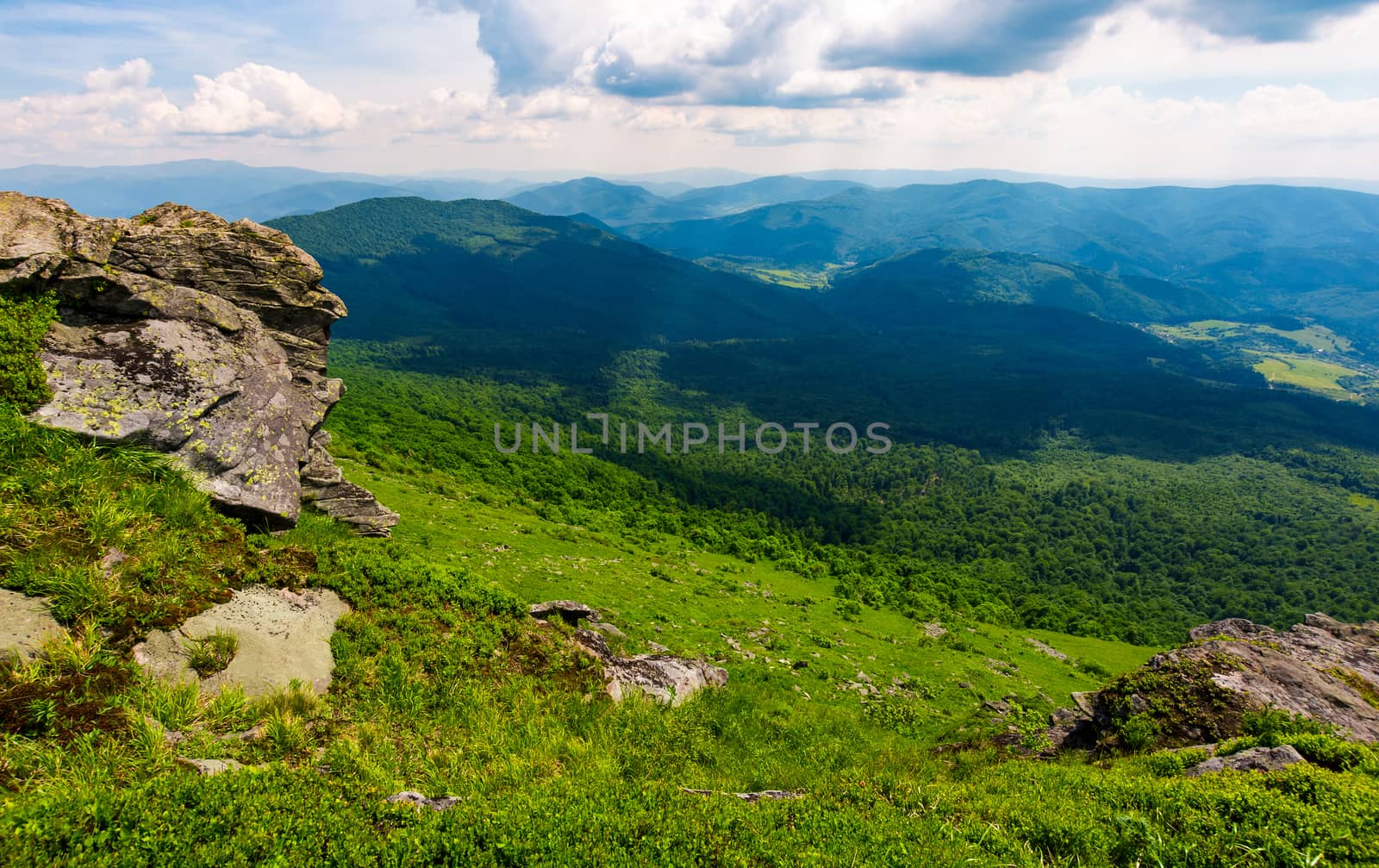 rocky cliff over the grassy valley. beautiful summer landscape with mountain ridge in the distance