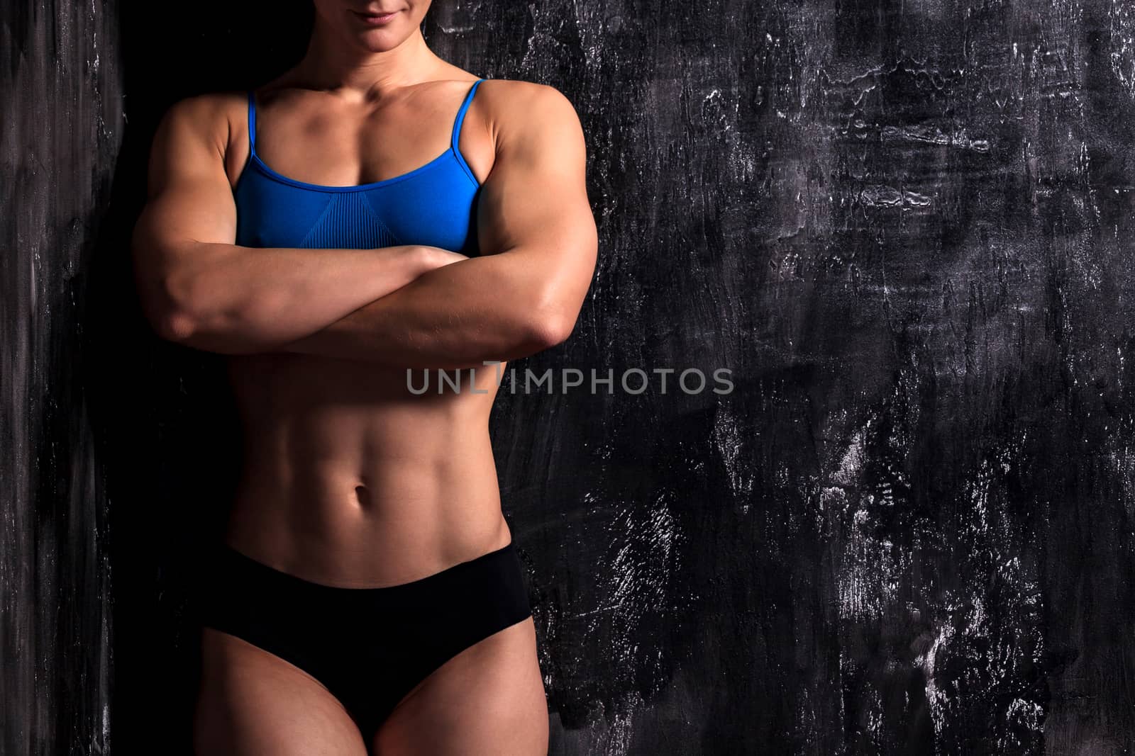 Muscular female torso wearing fitness clothing is posing against by Nobilior