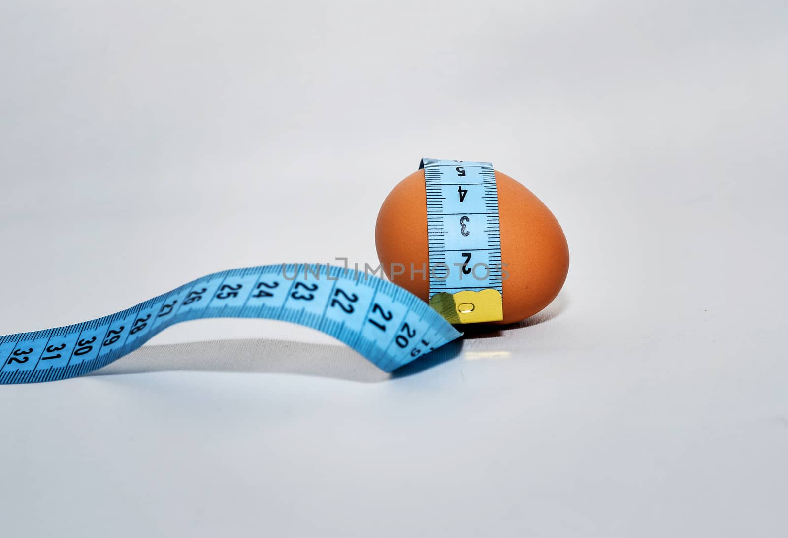 Egg wrapped in blue measuring tape, slimming concept.