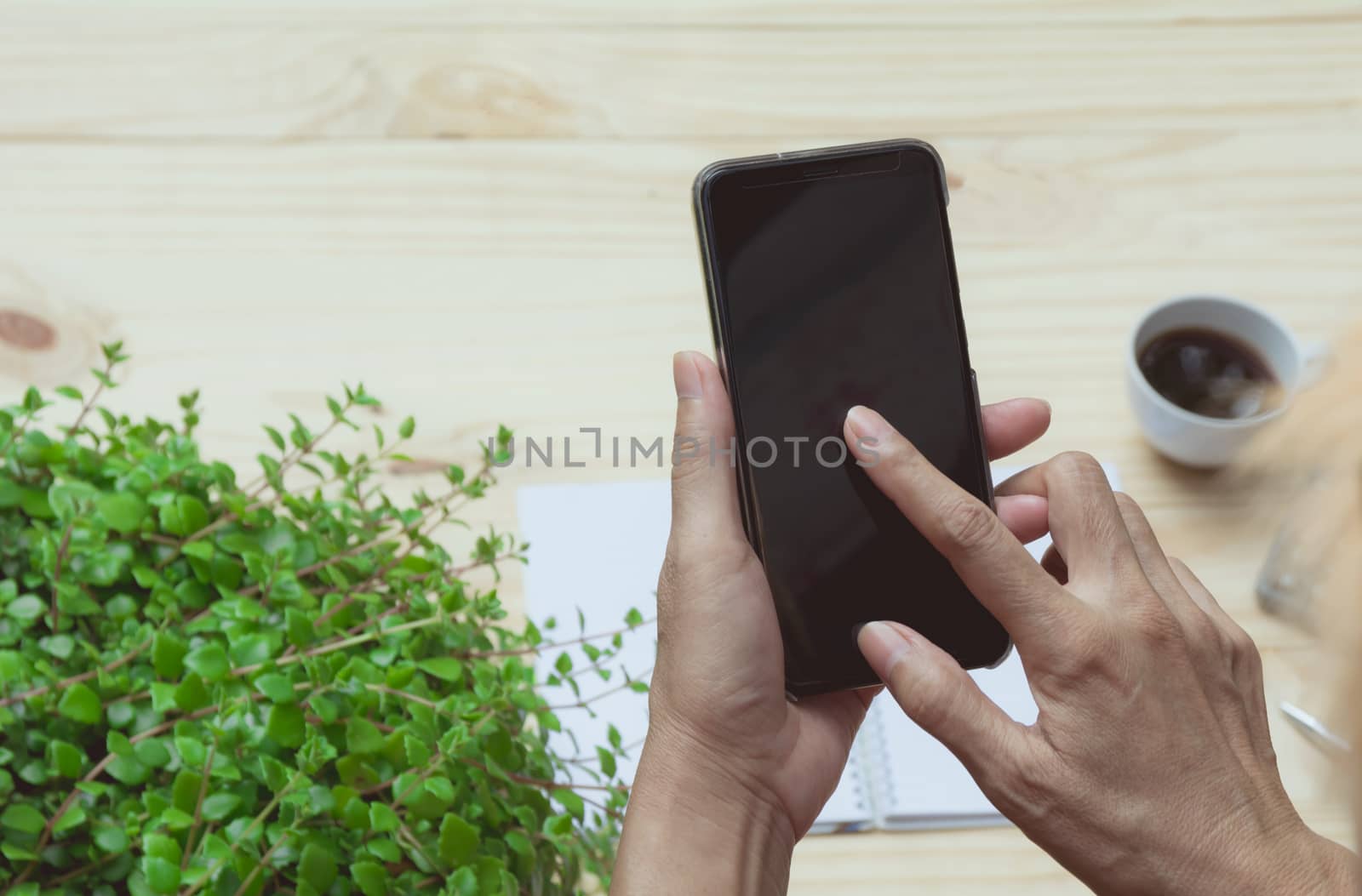 Hand using smart phone on wooden table background. Technology and communication concept.