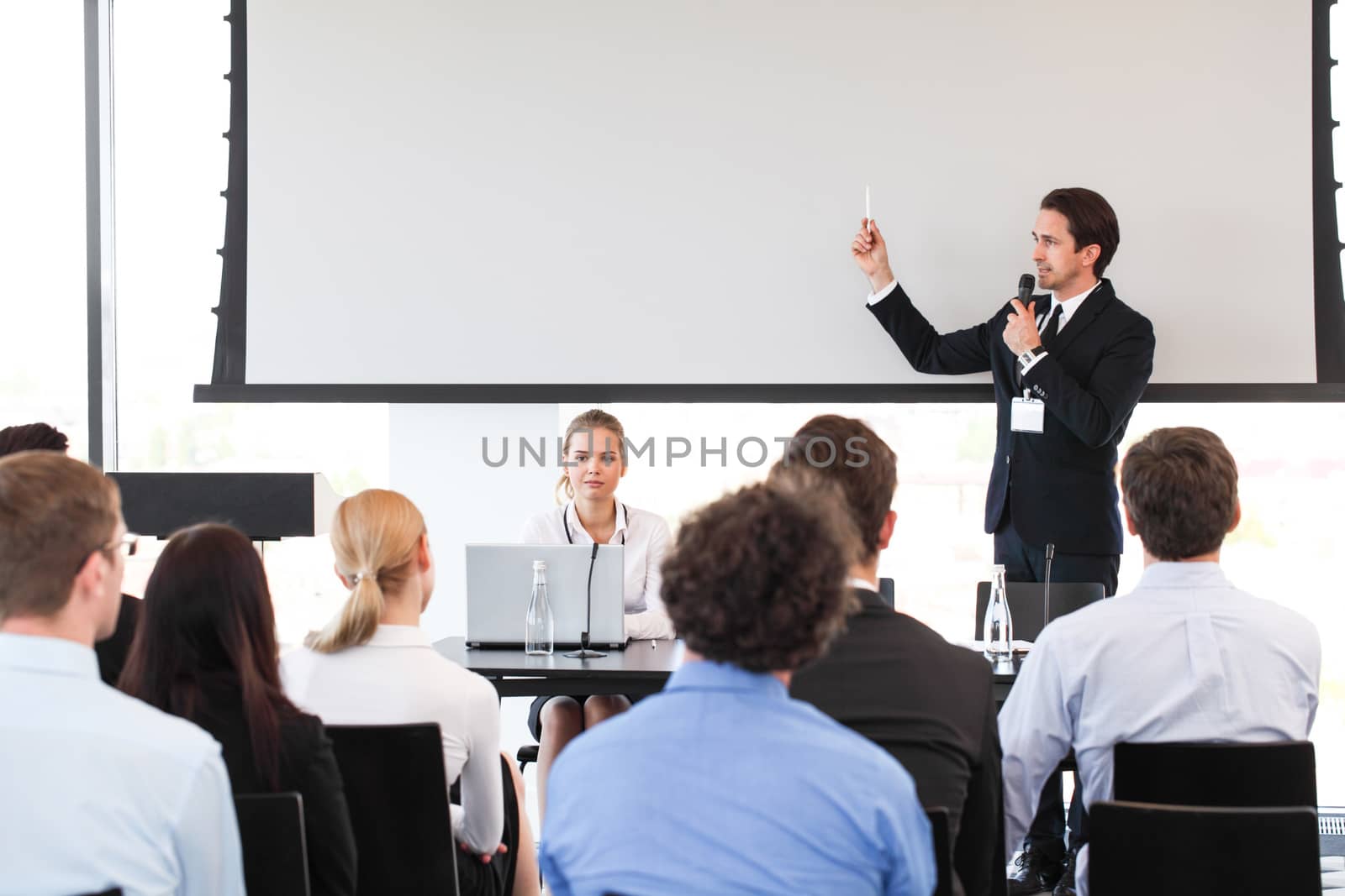 Speaker at business conference near white screen and audience