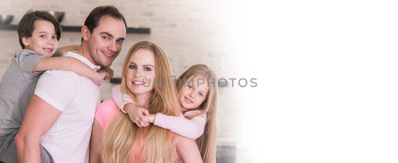 Portrait of happy family, father and mother giving boy and girl piggy back ride at home