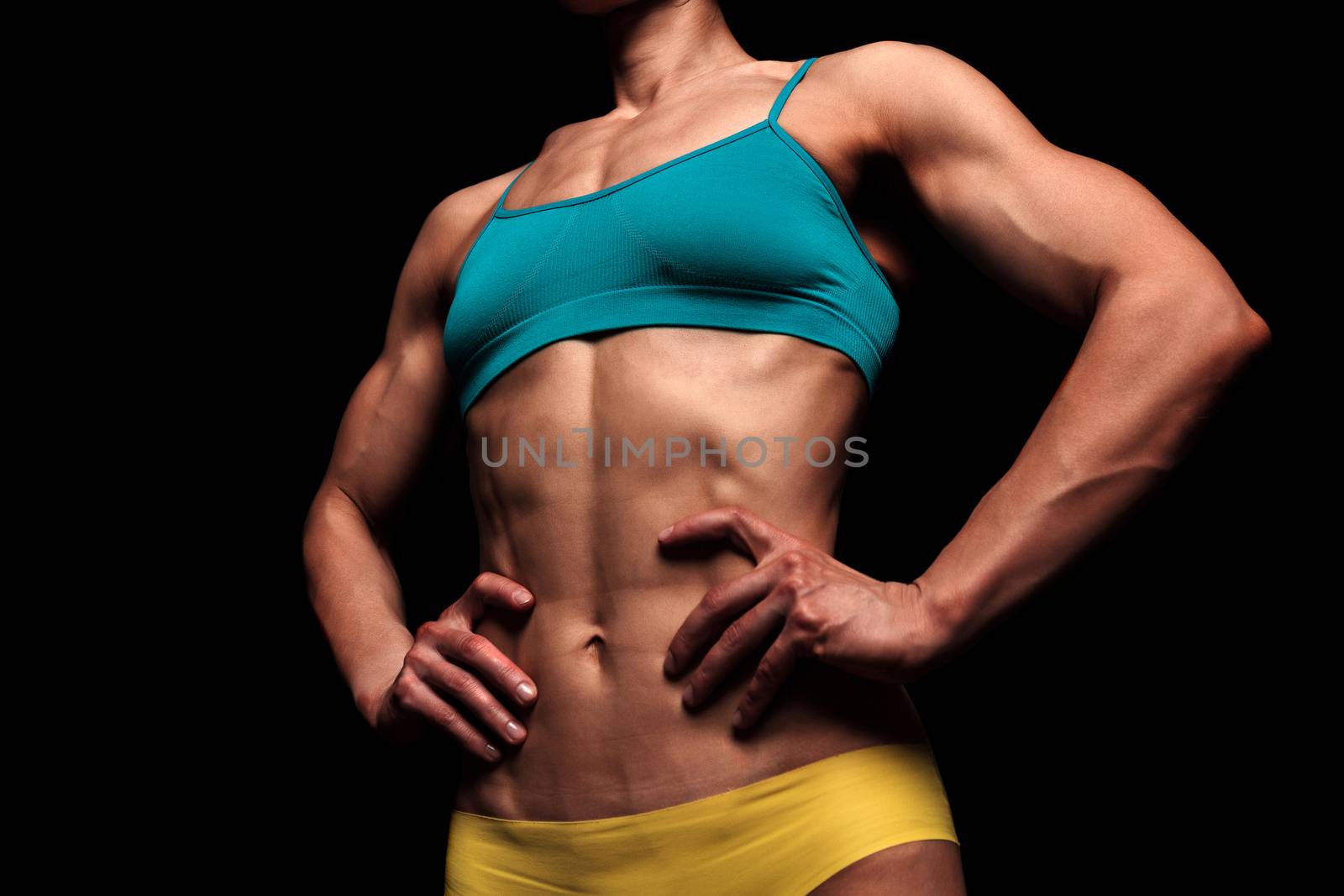 Fitness woman posing against a black background by Nobilior