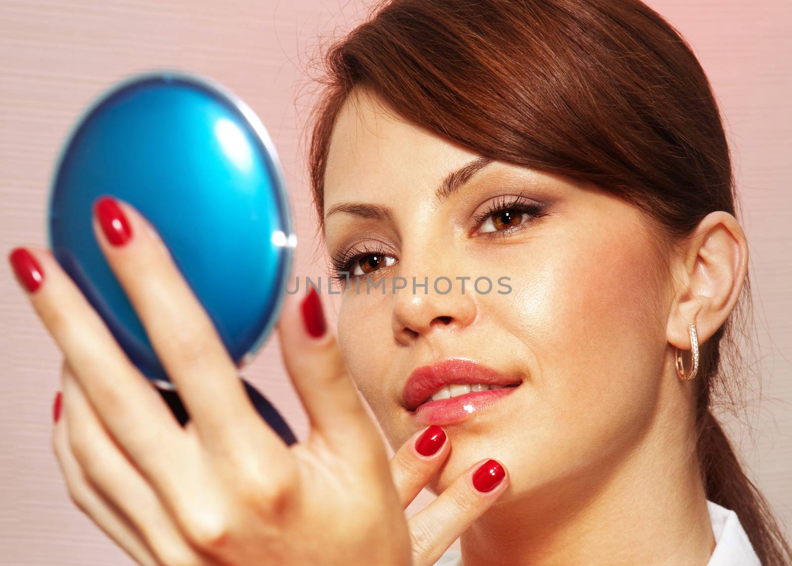 beautiful face smartens up in front of compact mirror