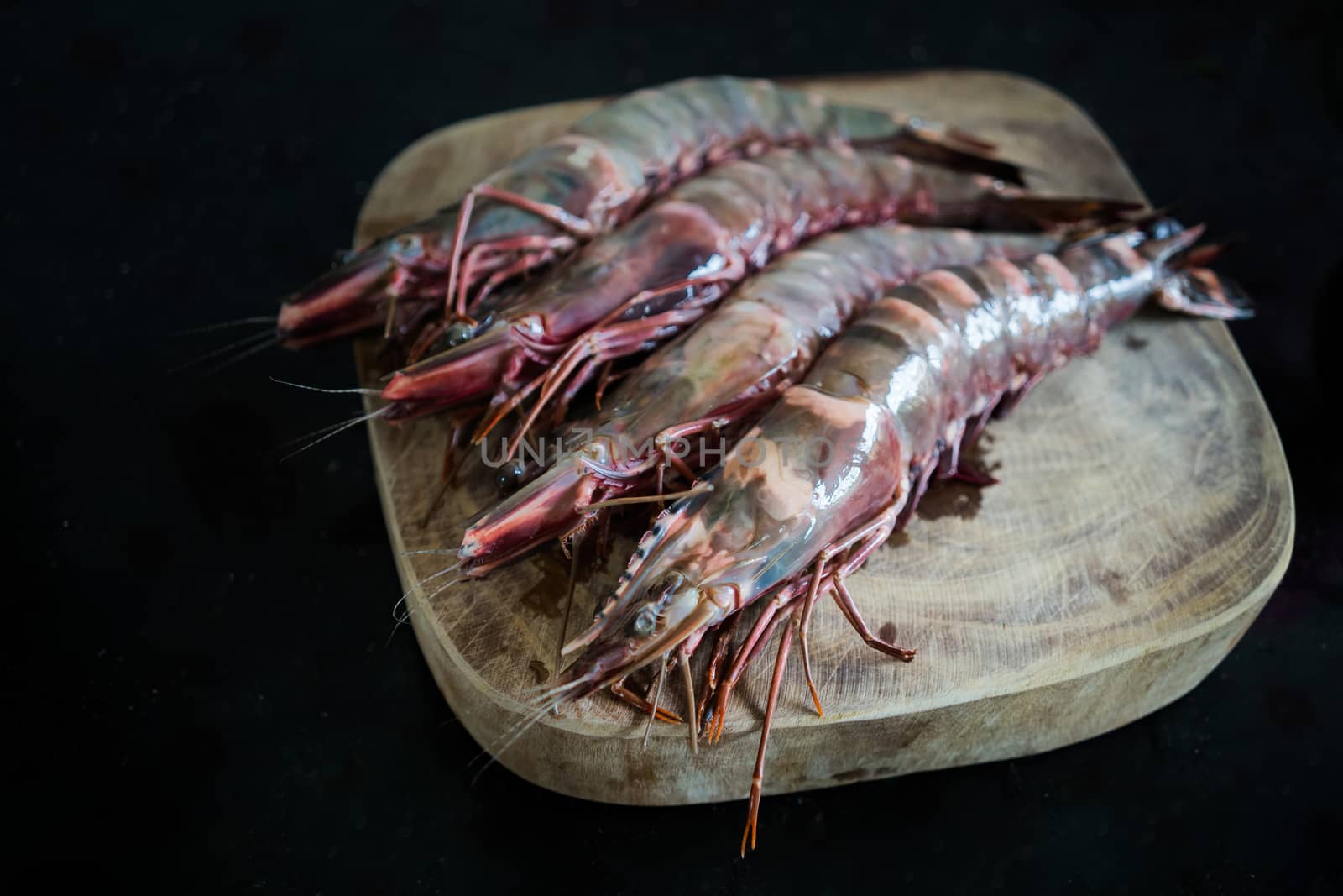 Four large king prawns on a chopping board