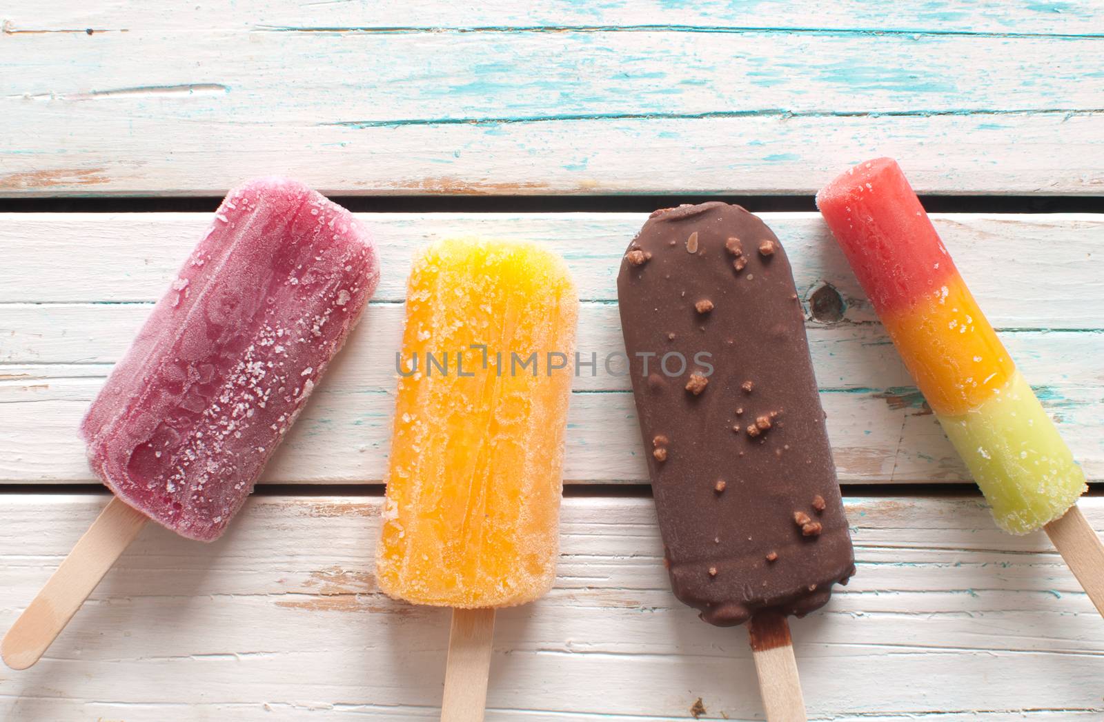 Assorted flavored ice lollies over a wooden background