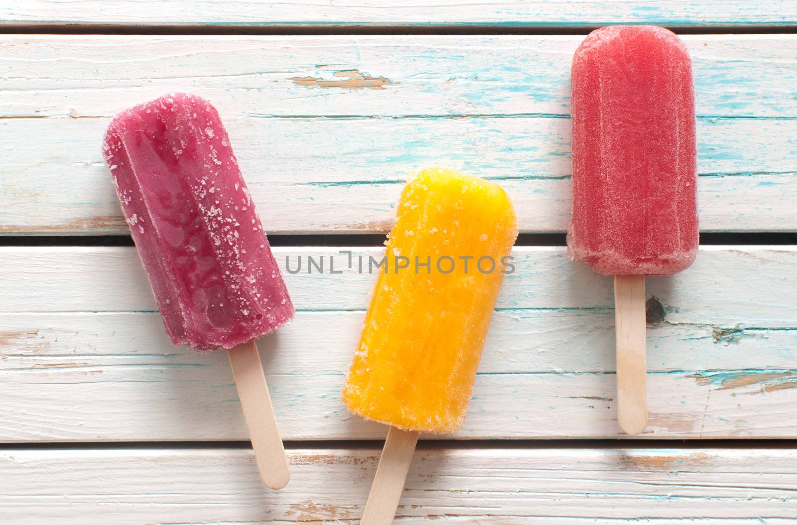 Assorted flavored ice lollies over a wooden background