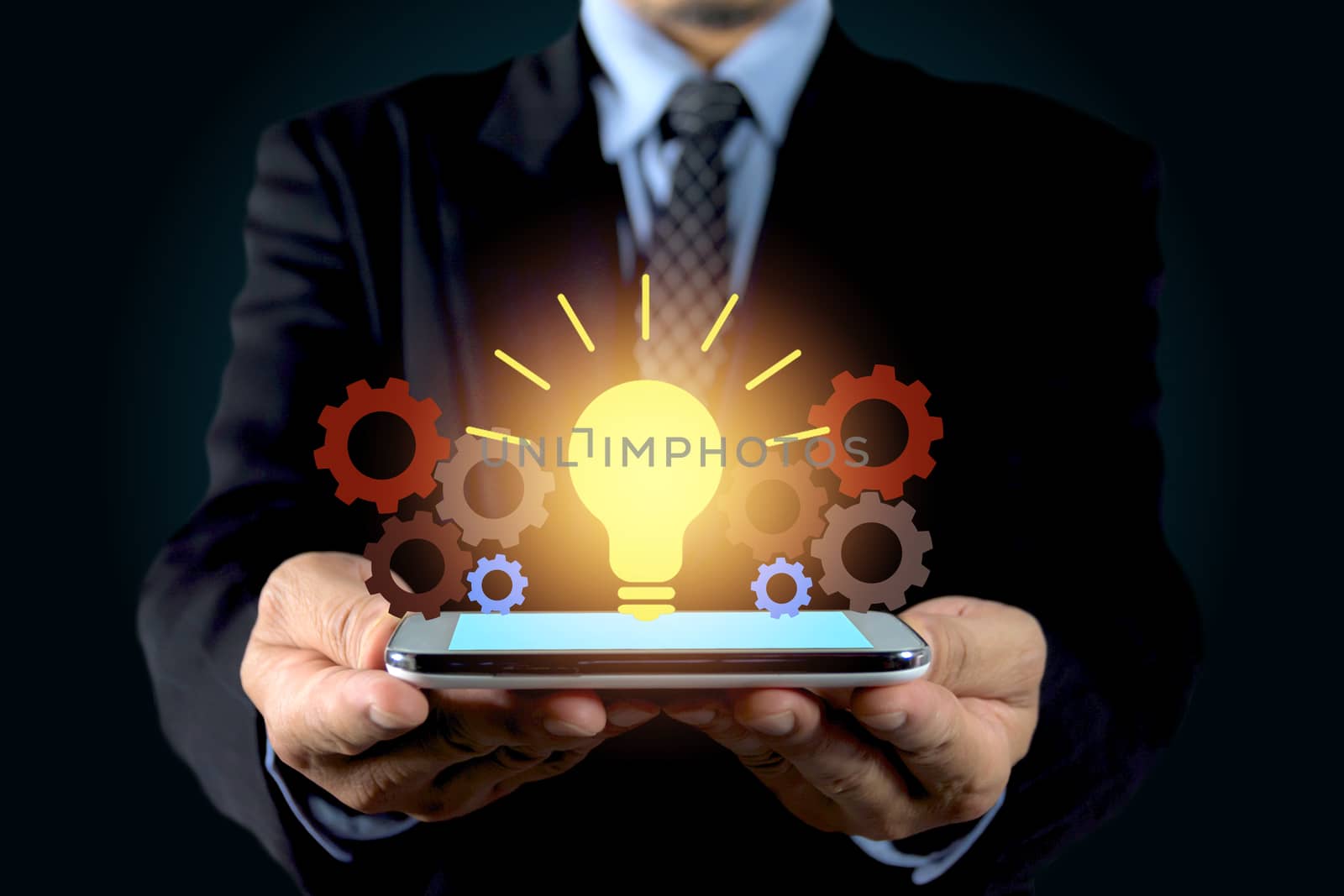 Double exposure close up of businessman hands holding glass light bulb with smart phone.