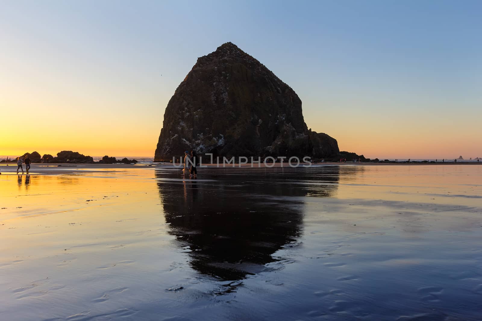 Beachcombers by Haystack Rock at Cannon Beach Oregon Coast low tide at sunset
