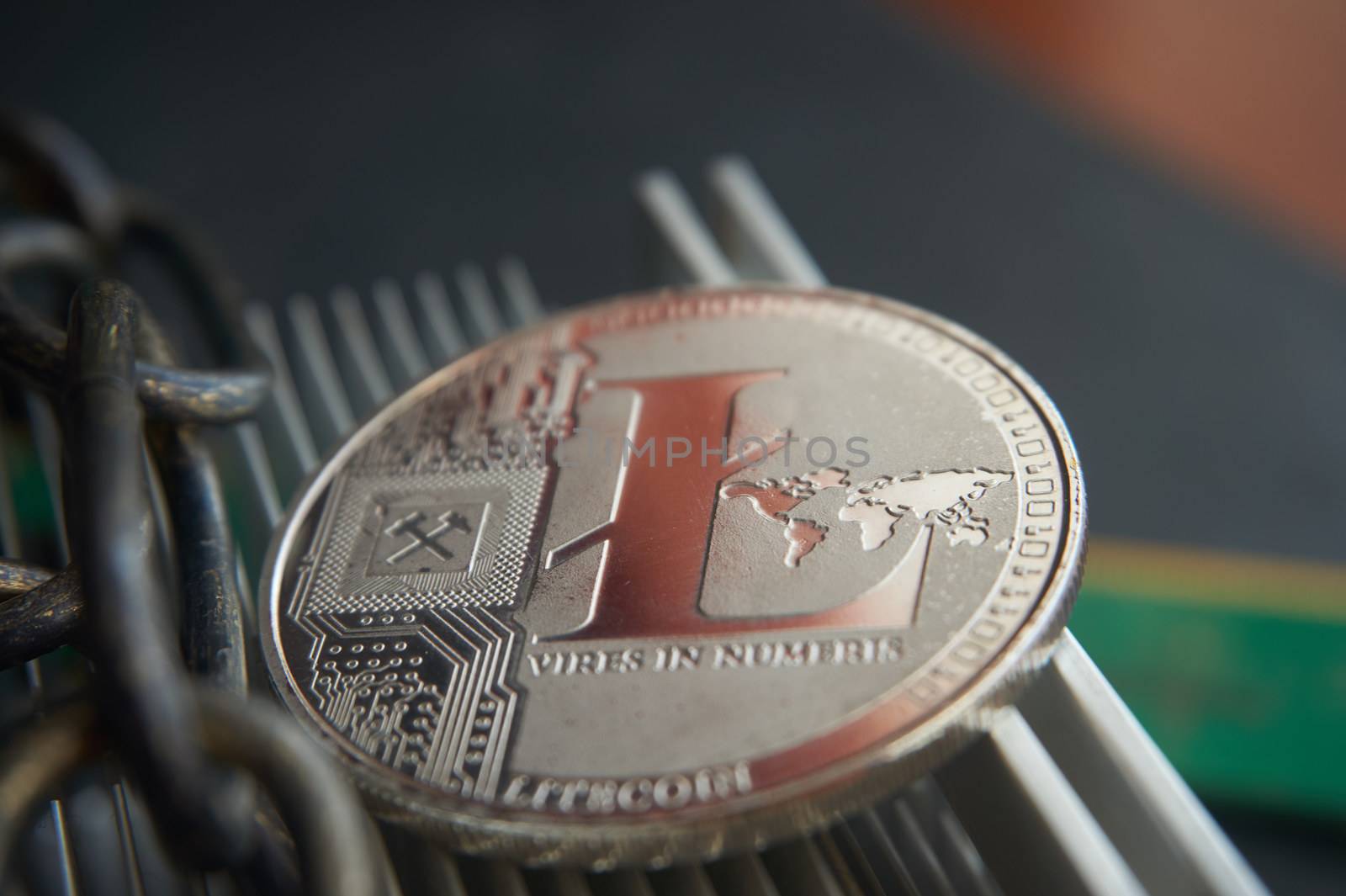 Silver litecoin coin  lying on the  aluminum computer cooler next to a copper chain. Cryptocurrency digging difficulty, blockchain and network concept, selective focus.
