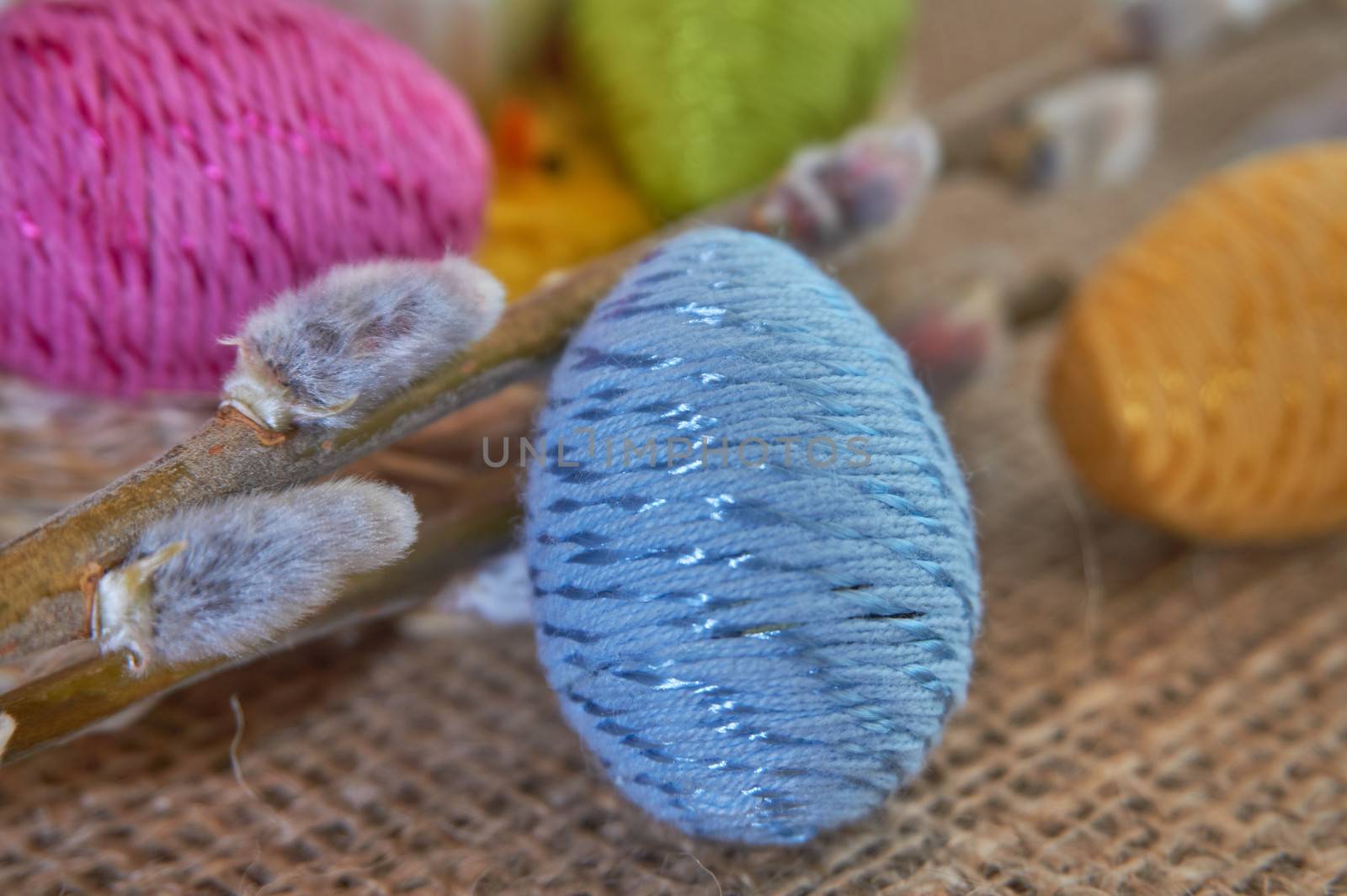 Colorful easter eggs and willow branch on natural jute fabric background. The concept of a happy Easter
