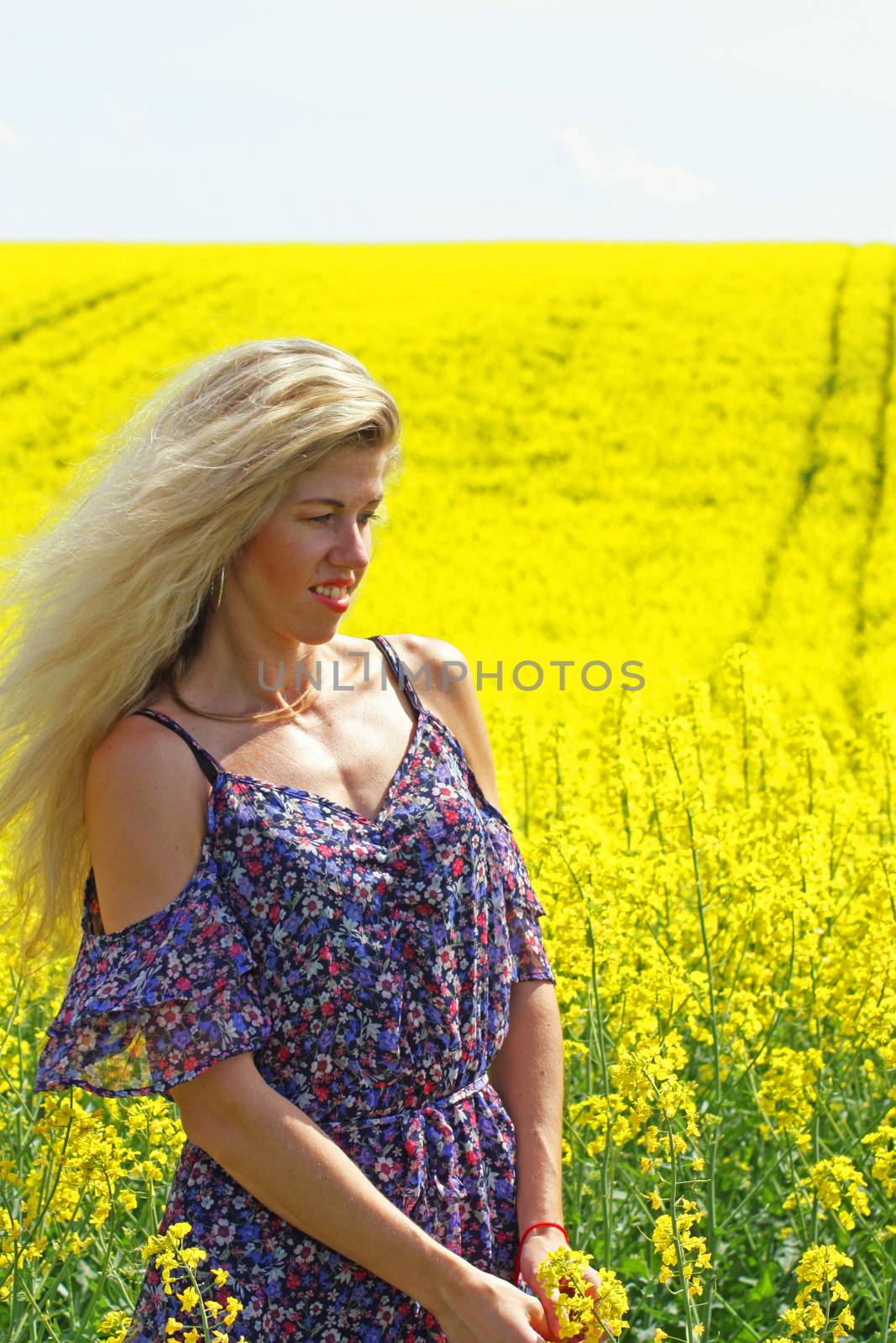 Blonde peasant girl in floral print dress on the rapeseed field by zakob337