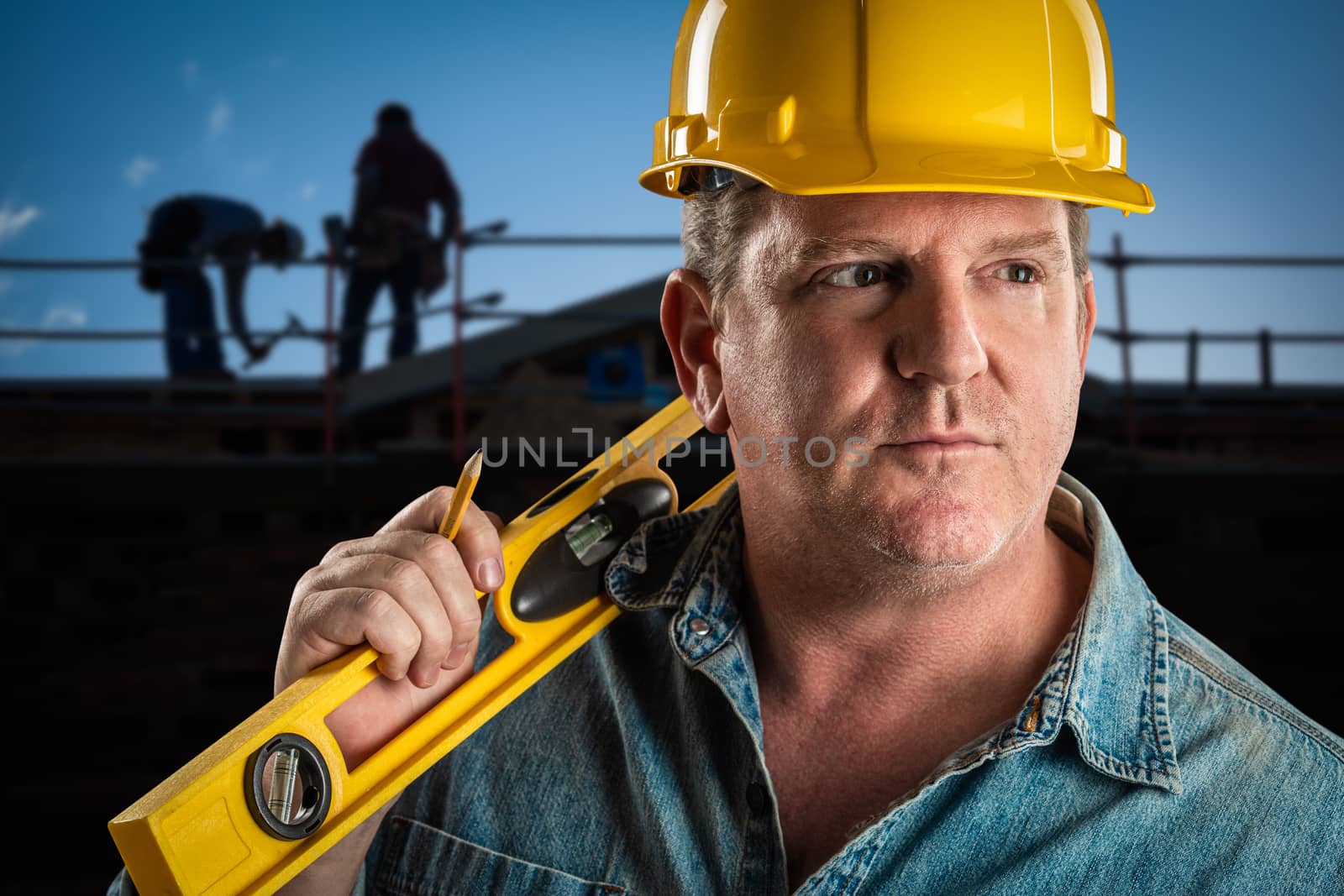 Serious Contractor in Hard Hat Holding Level and Pencil At Construction Site. by Feverpitched