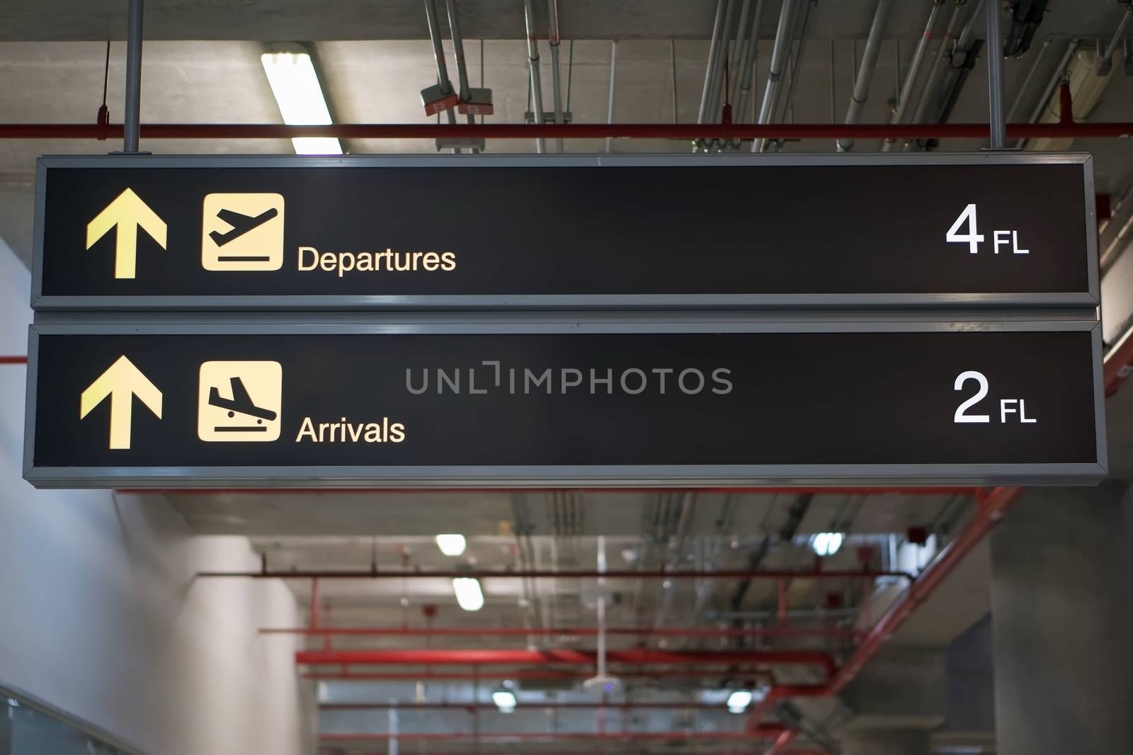 Departure and arrivals information board sign with yellow and white character on black background at international airport terminal.