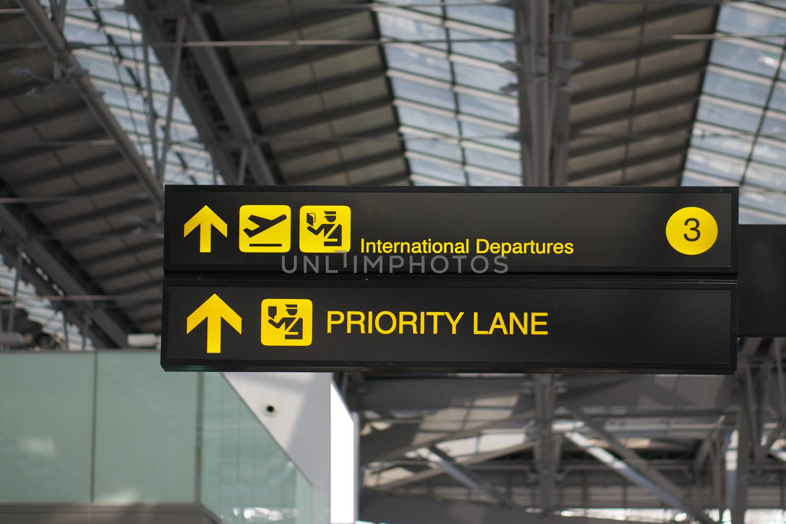 Departure and priority lane information board sign with yellow and white character on black background at international airport terminal.