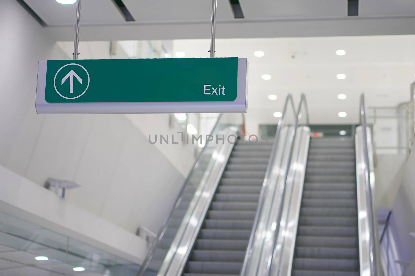 Exit information green board sign have blur escalator as background by eaglesky