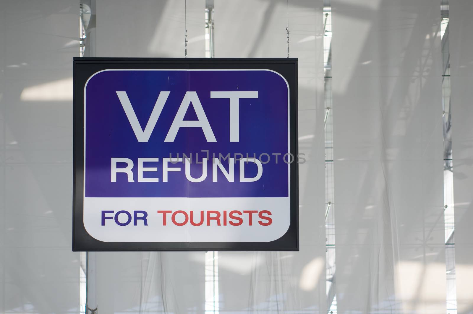 Vat refund for tourists information board sign with red and white character on blue background at international airport terminal.