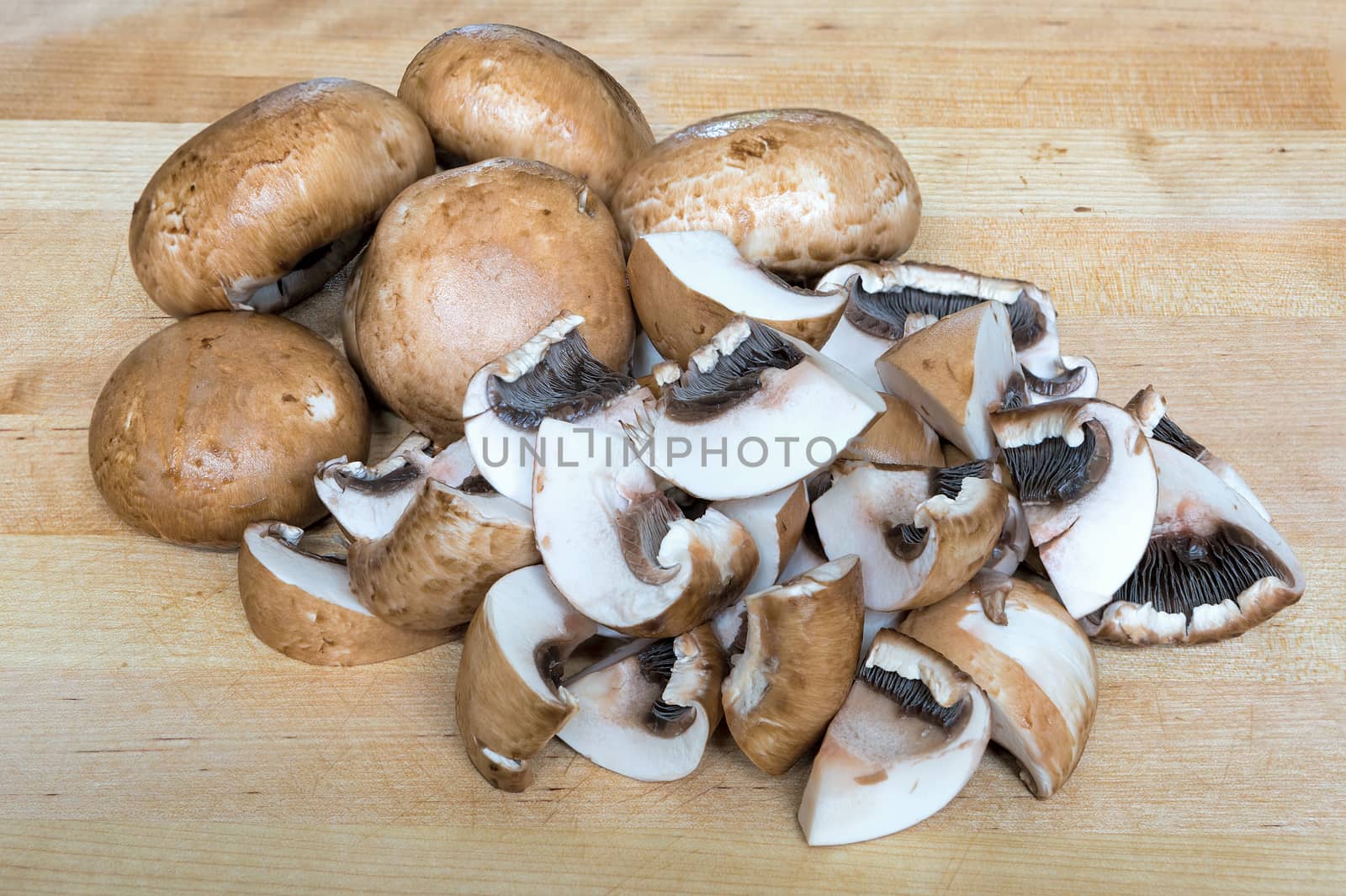 Baby Portobello mushrooms whole and sliced on wood cutting board closeup macro