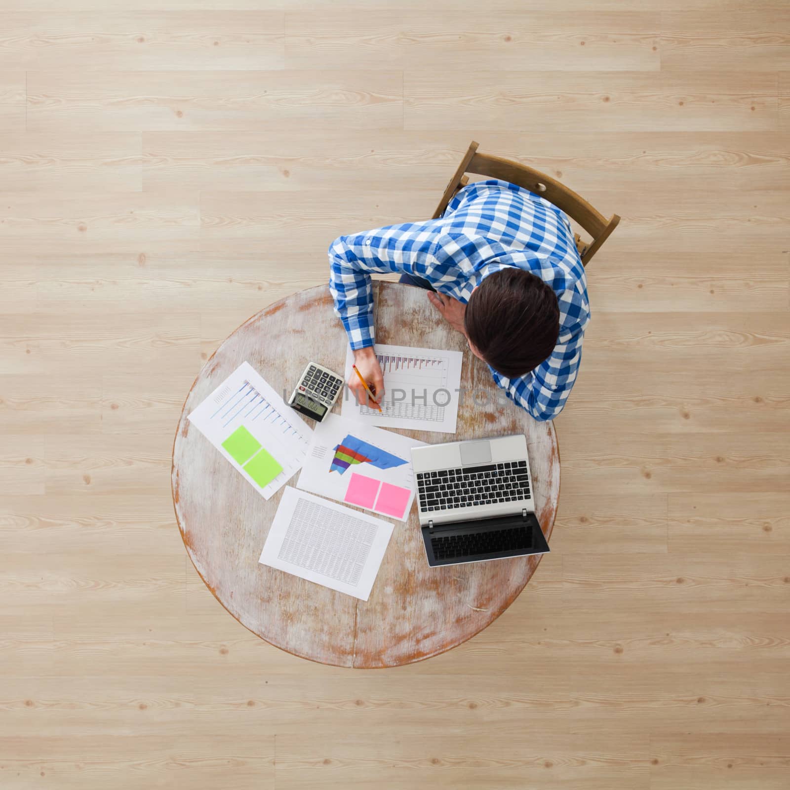 Businessman working with finance documents at office with laptop, and graph data papers on his desk, top view with copy space