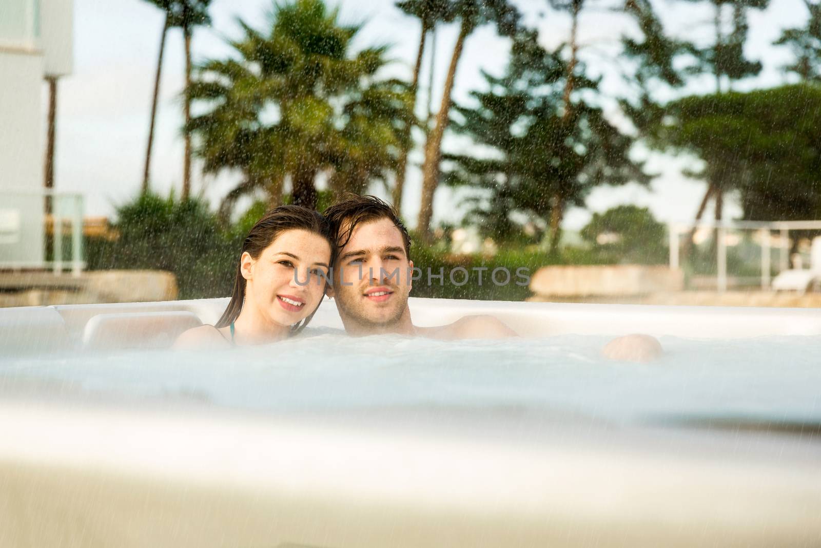 Young couple in a luxury hotel inside a jacuzzi in a rainy day 