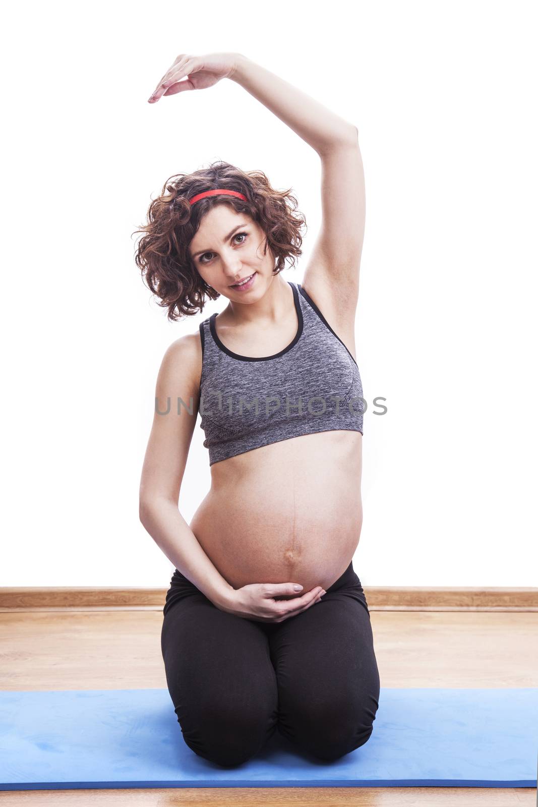 young pregnant woman exercises on the mat. Isolated shot