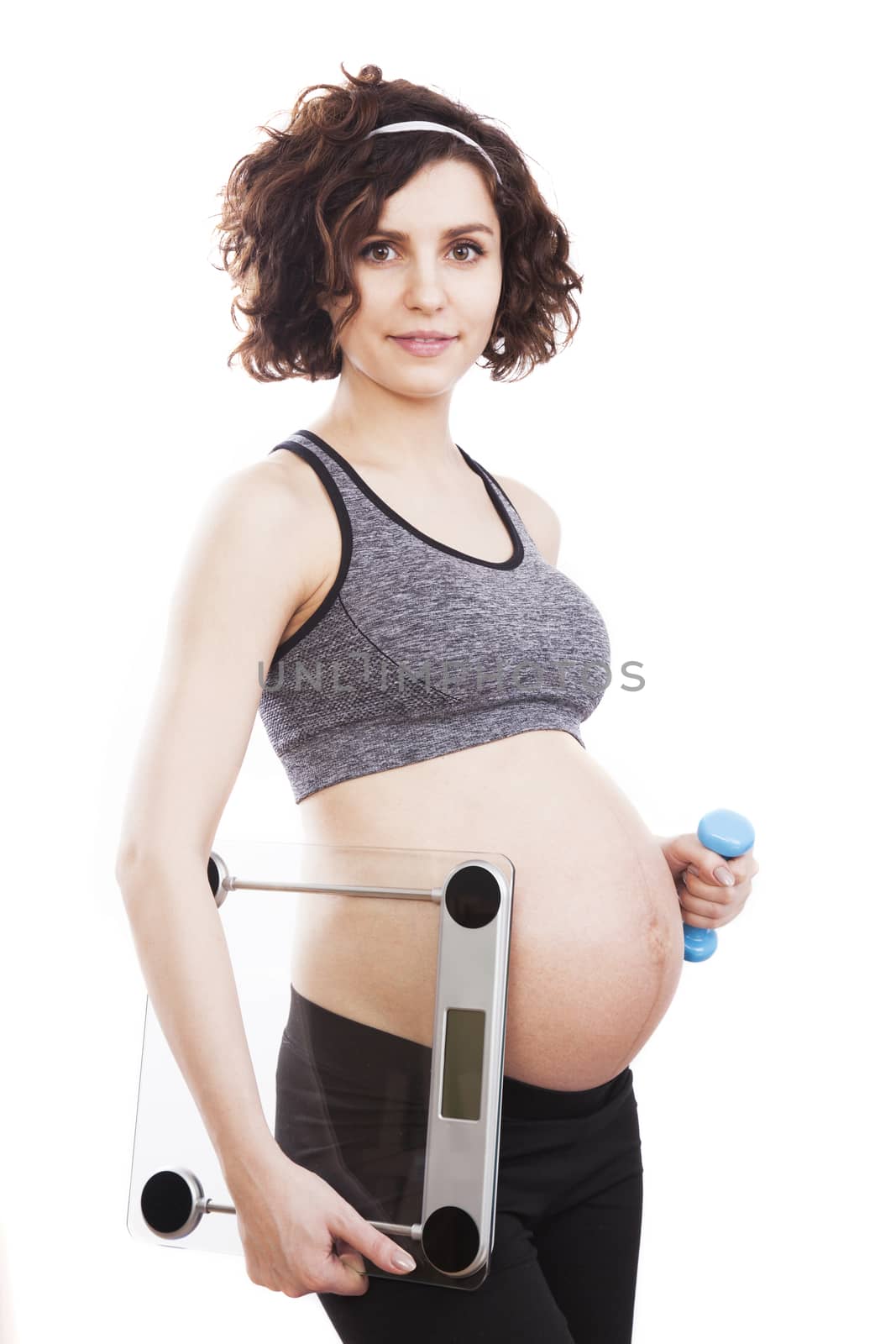 Young pregnant woman holding weight. Studio shot, isolated