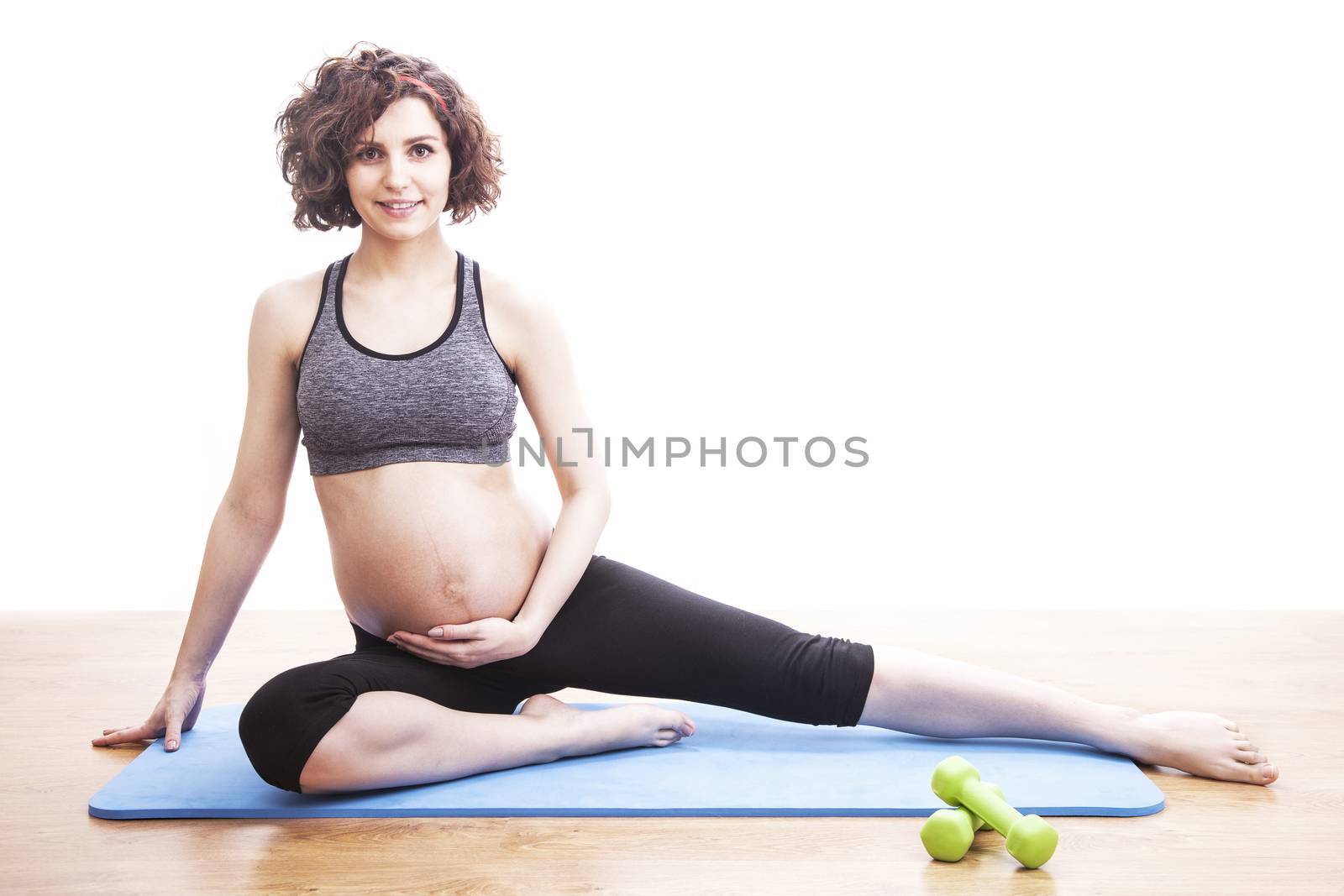 young pregnant woman exercises on the mat. Isolated shot