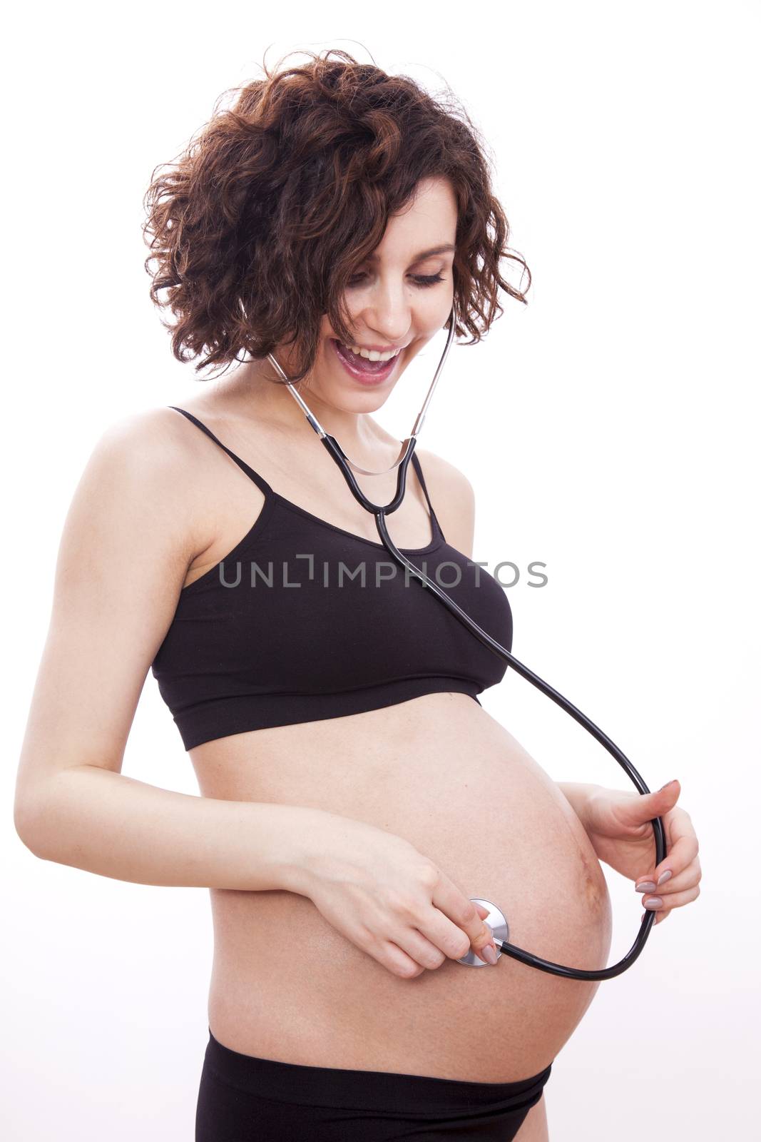 Pregnant woman listens to her child through a stethoscope.