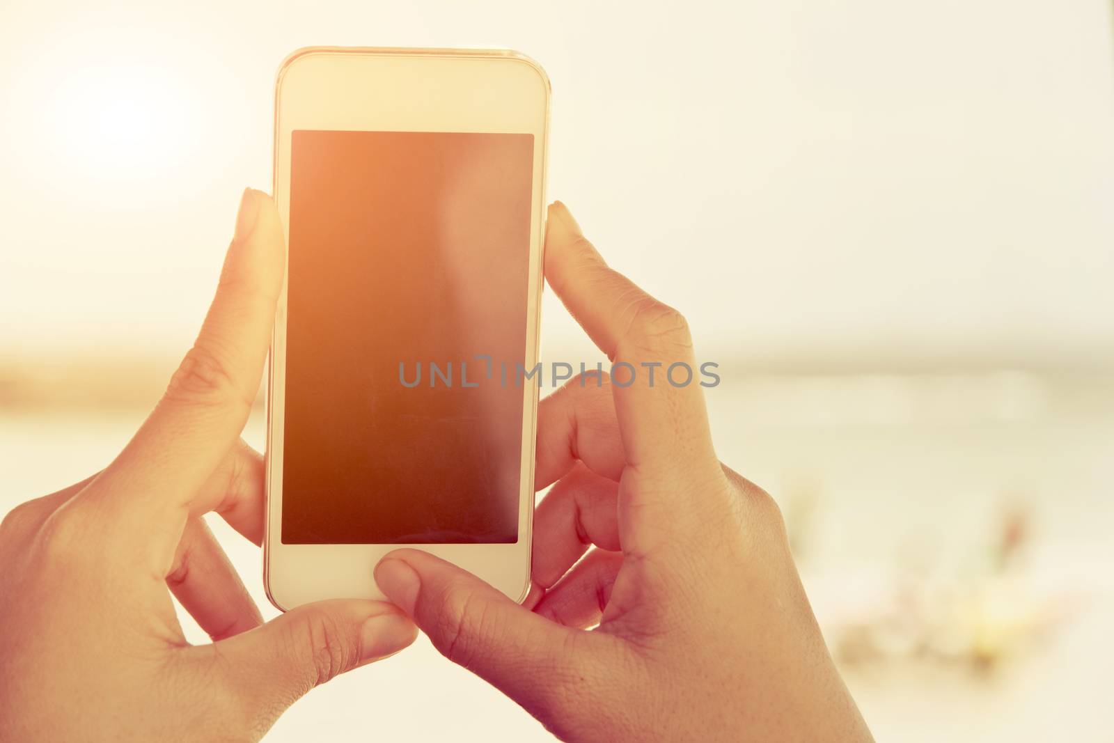 Close-up of female hands using smart phone with flare light background. Searching Internet ,Social Networking Concept