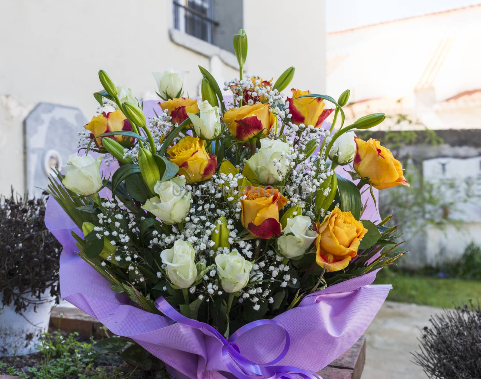 bouquet of flowers as roses and mlily in purple wrap 