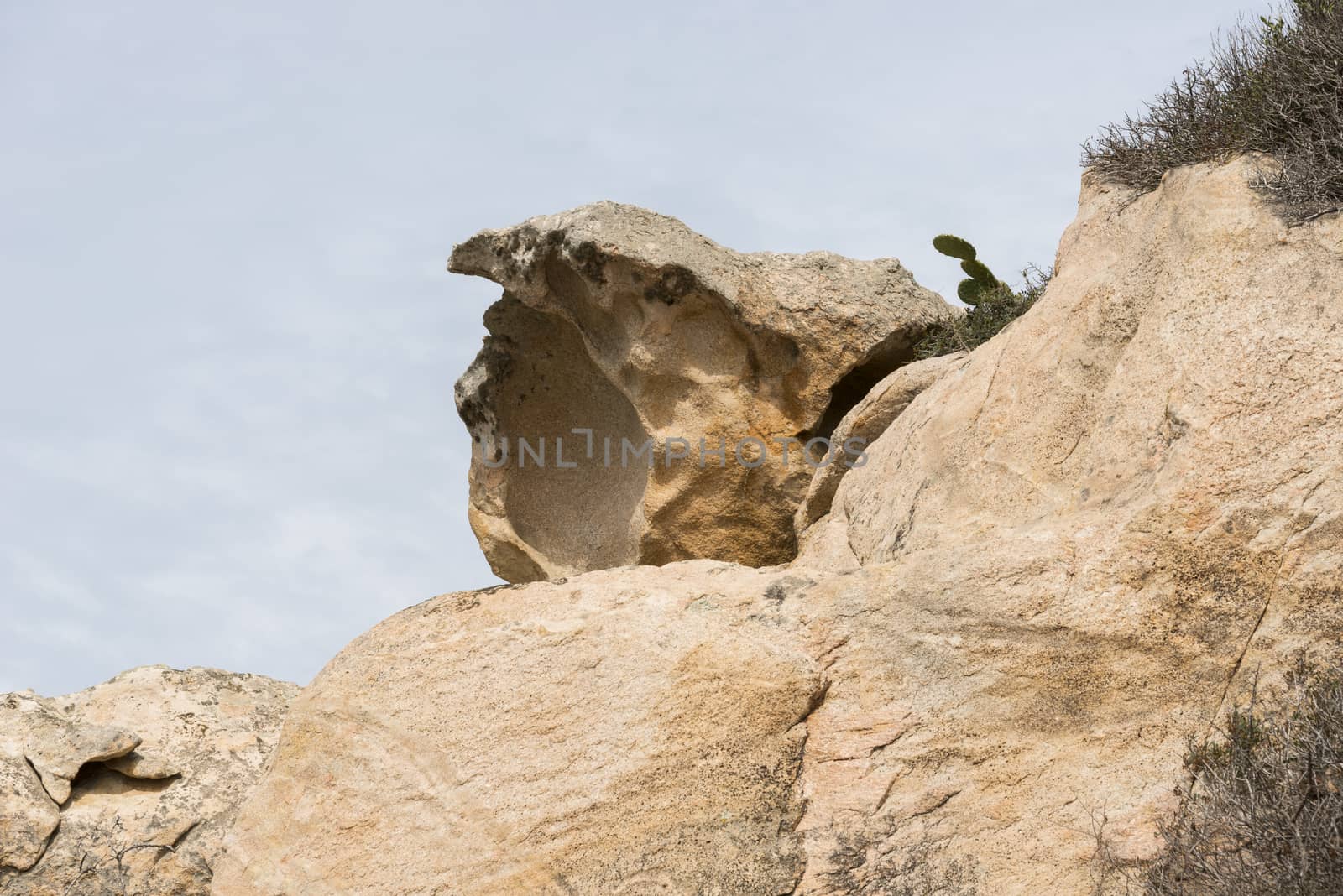 big brown rock on maddalena island with blue sky as background