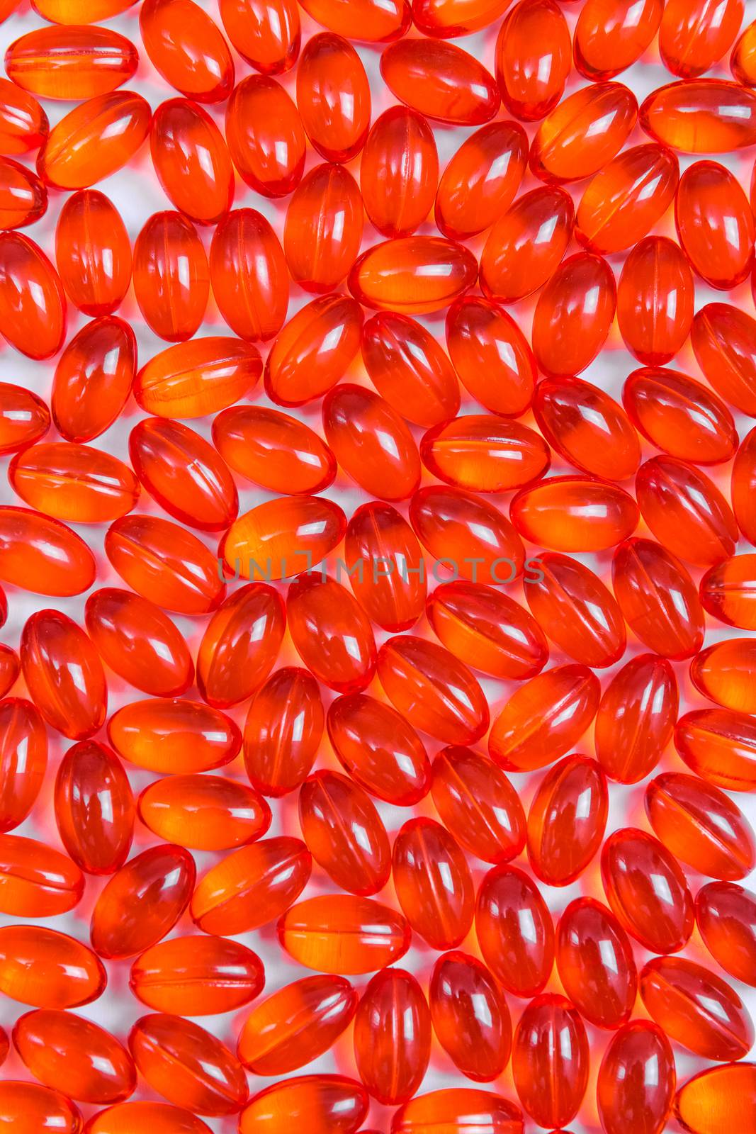 Red shiny pills background. Capsules with medicine on white surface.