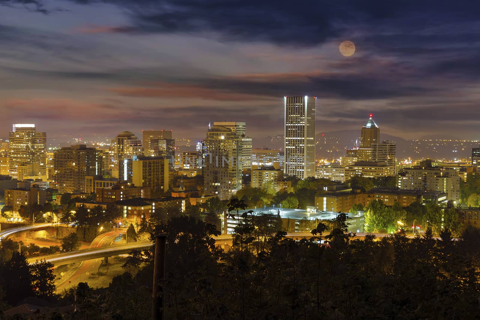 Full moon rising over Portland Oregon downtown cityscape at night