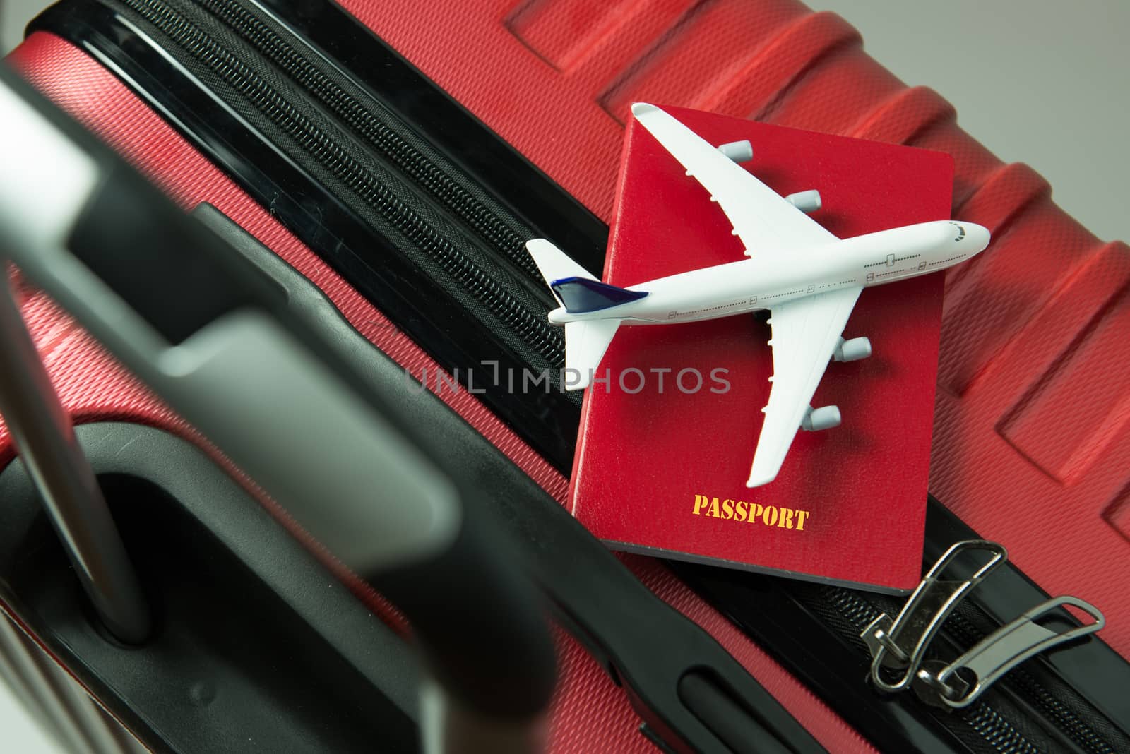 Red passport and airplane model on red luggage by Kenishirotie