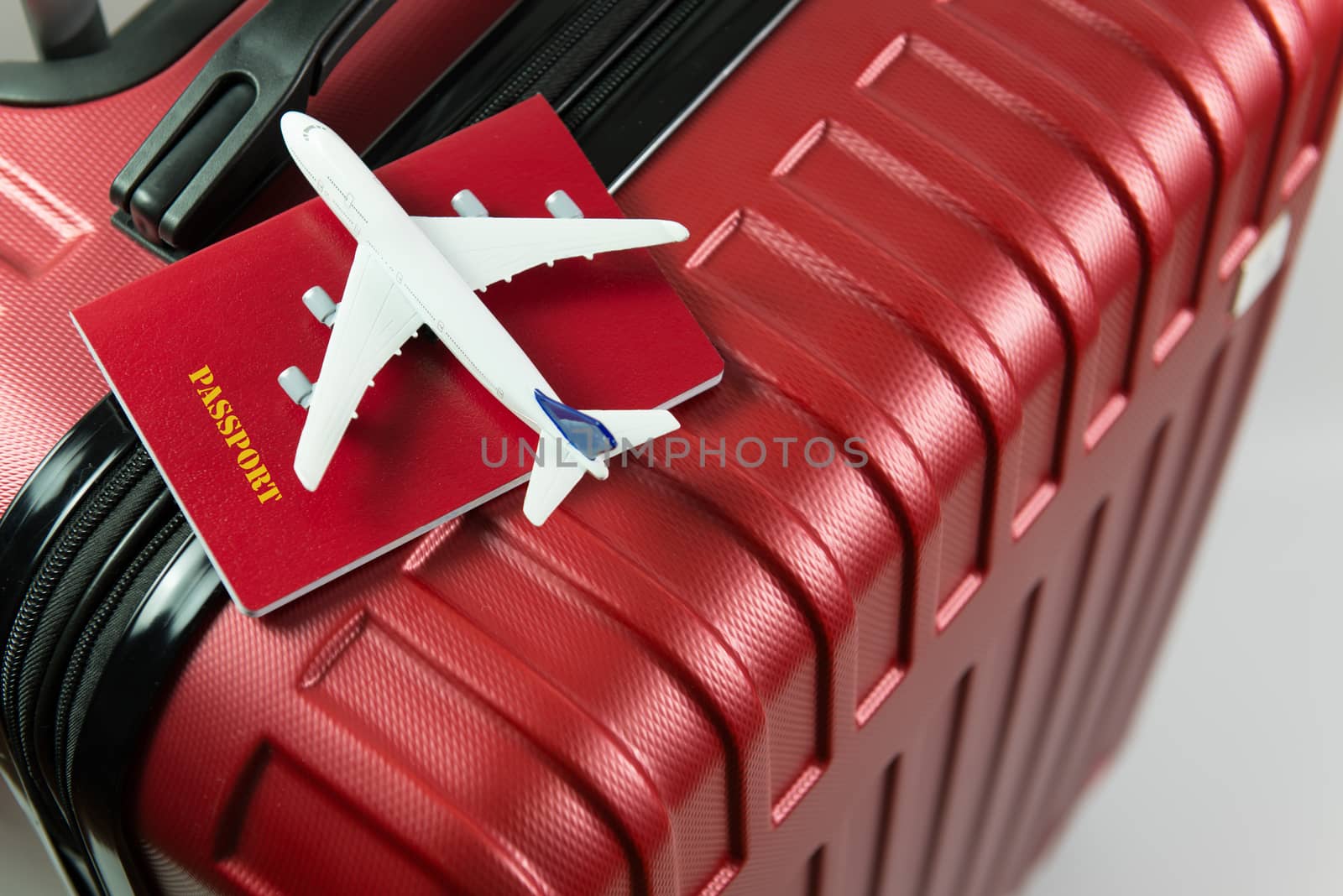 Red passport and airplane model on red luggage by Kenishirotie