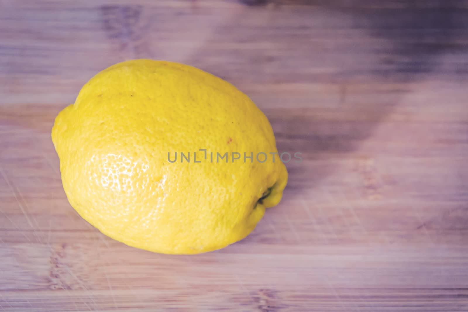 Close up shot of a delicious, juicy lemon on a wooden cutting board ready to be sliced and eaten