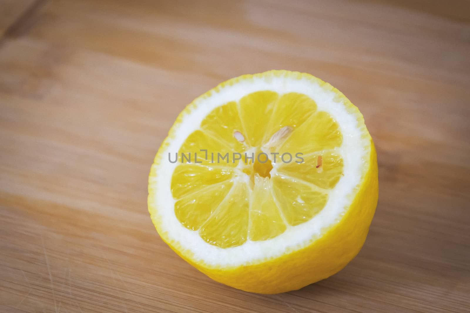 Half of a lemon with a bone on a light wooden board