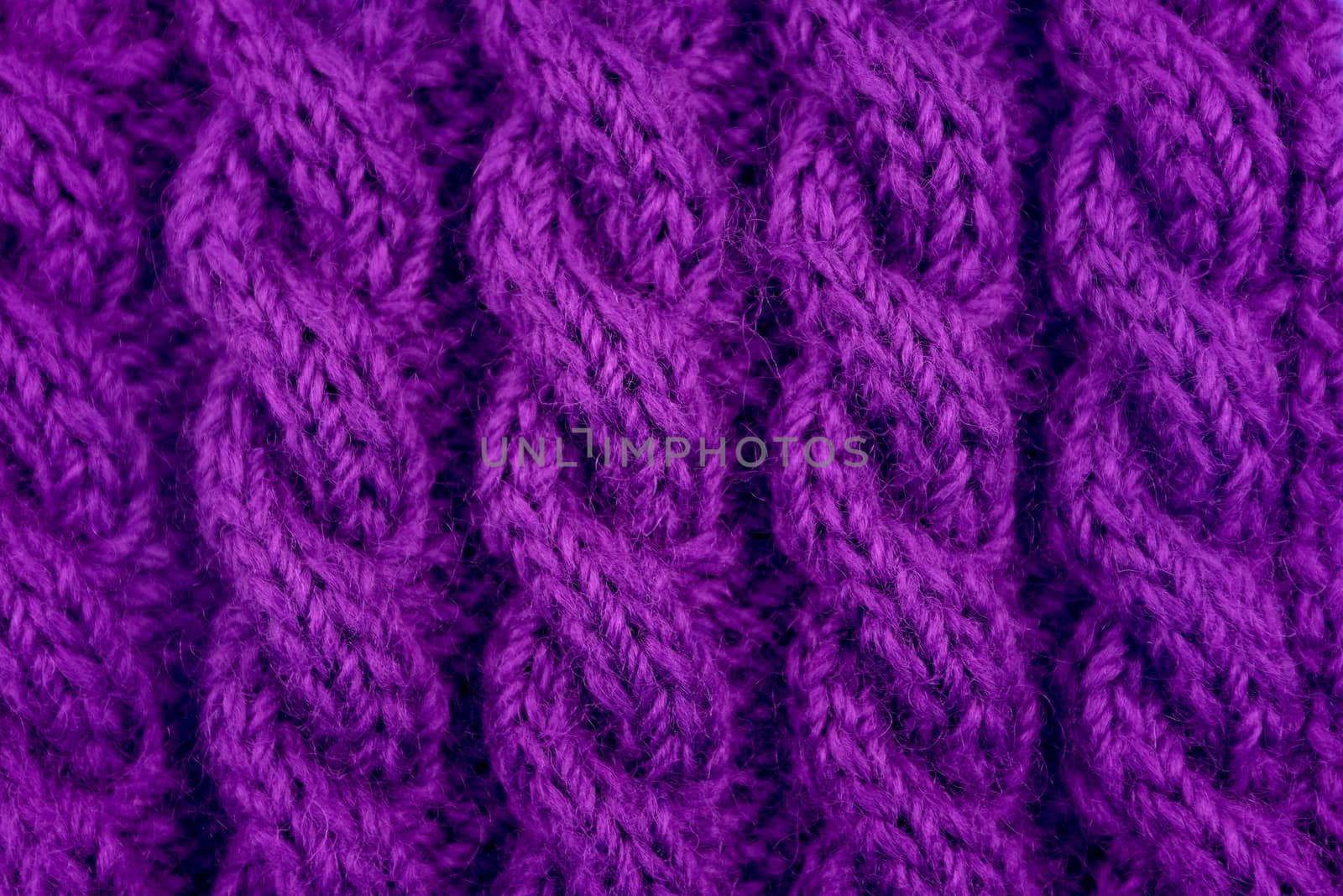 Detail of purple handknit coiled rope cable knitting stitch as abstract background