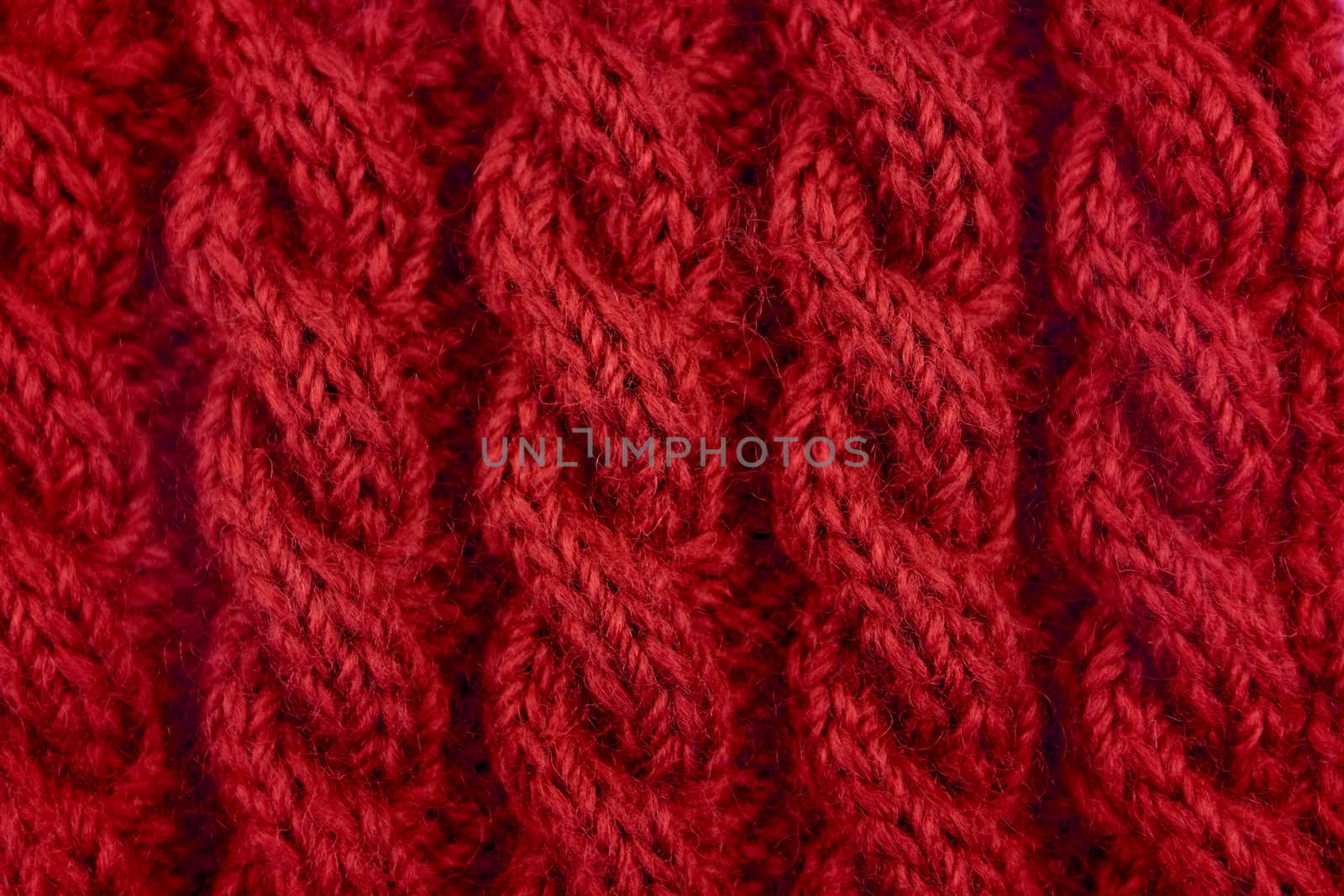 Detail of red handknit coiled rope cable knitting stitch as abstract background