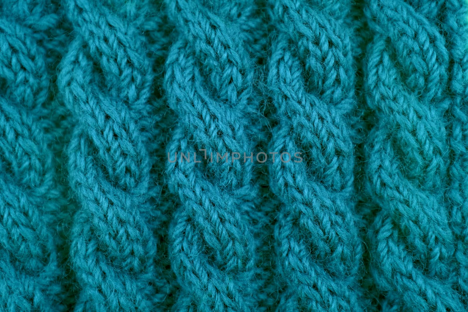Detail of teal handknit coiled rope cable knitting stitch as abstract background