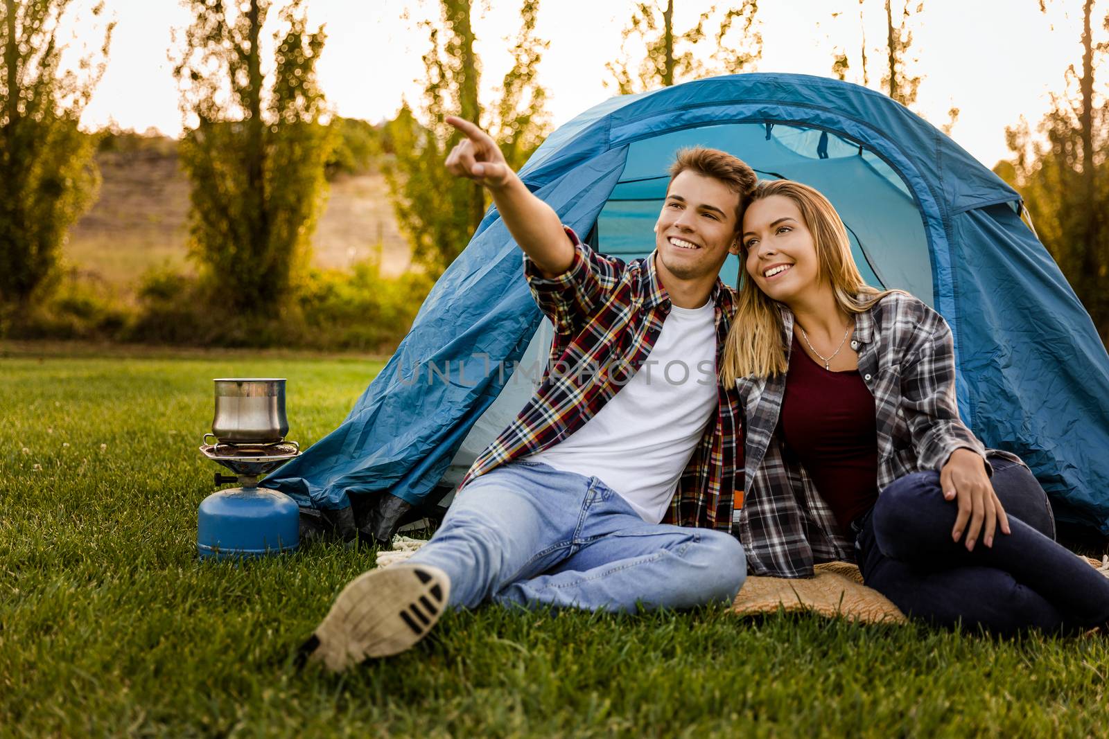 Shot of a happy couple camping on the nature and pointing to somewhere