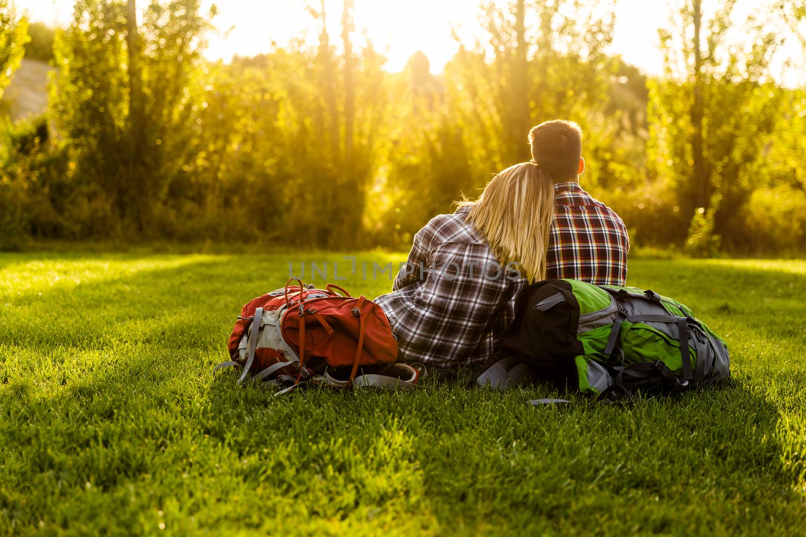 Young couple with backpacks sitting on the grass