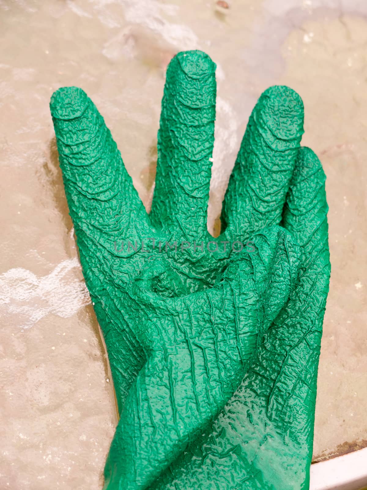 a wet single green gloves on glass table; Essex; UK