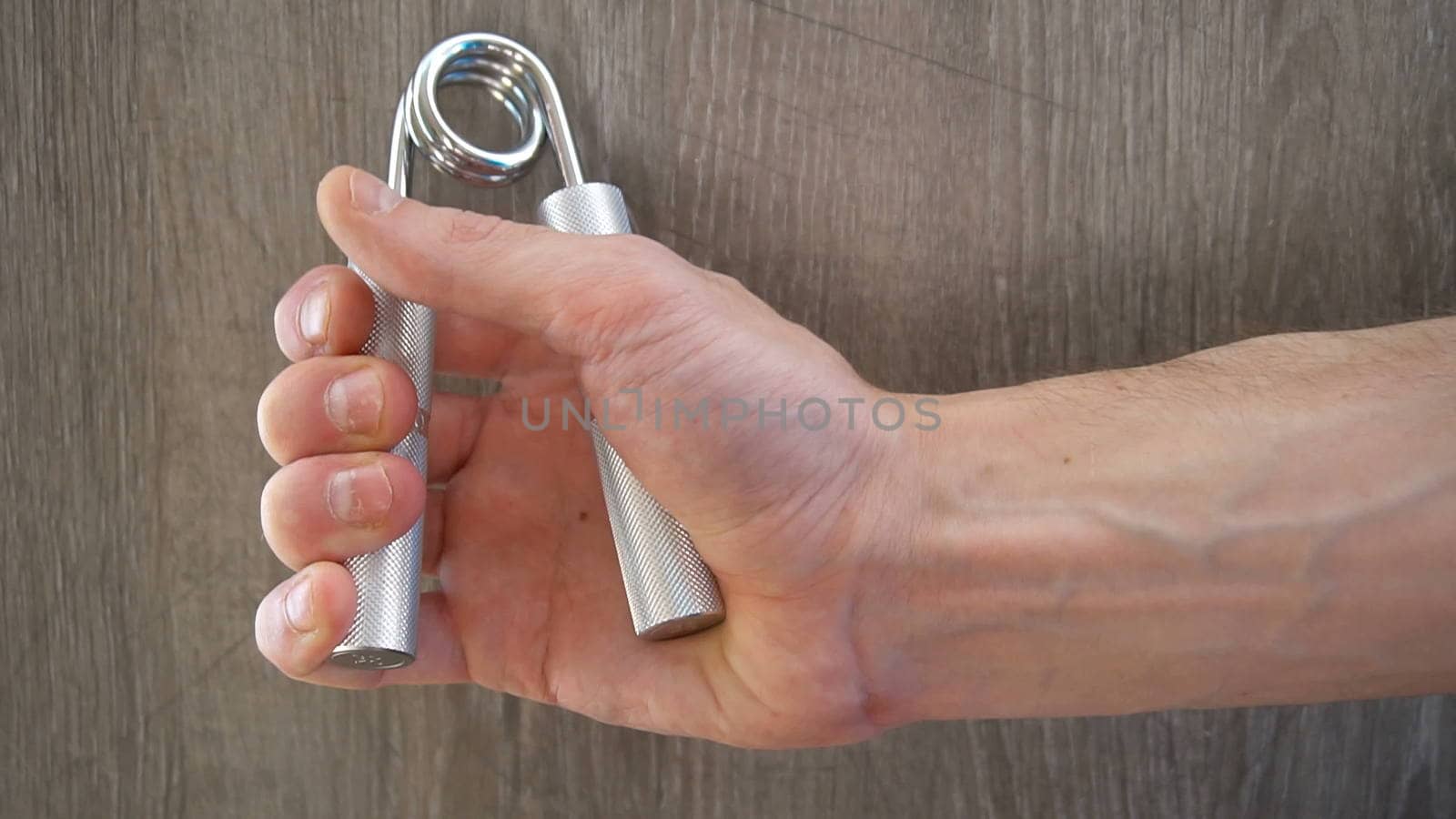 young athlete compresses and decompresses silver metallic manual expander.