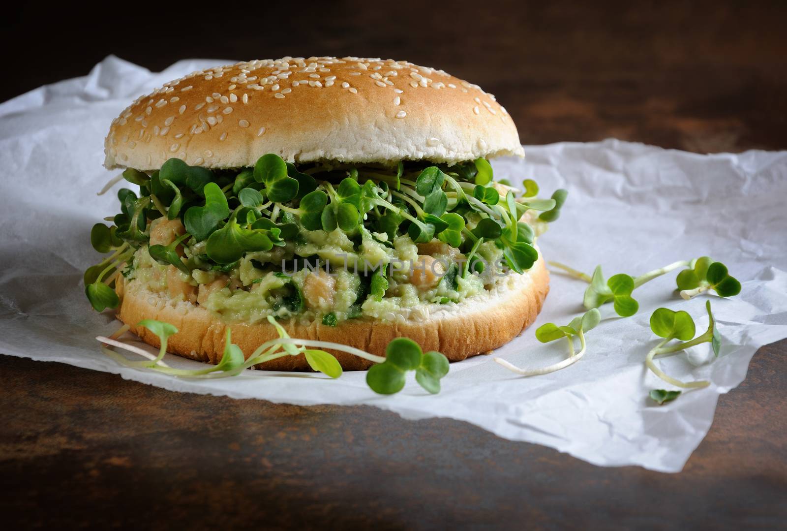 A vegetarian burger made from a gluten-free bun with chickpeas, avocado and herbs, radish sprouts. A quick and healthy lunch idea that you feel energized throughout the day.