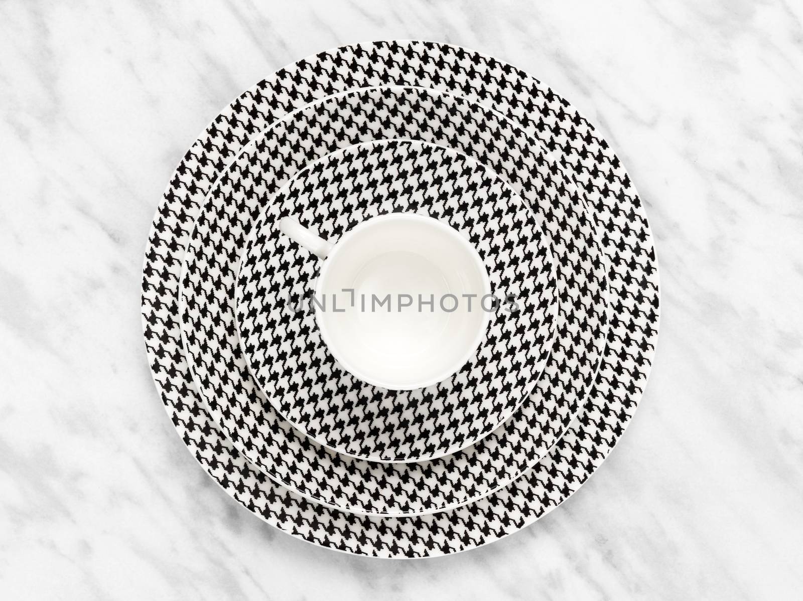 Black and white coffee cup with a set of saucers on marble background.