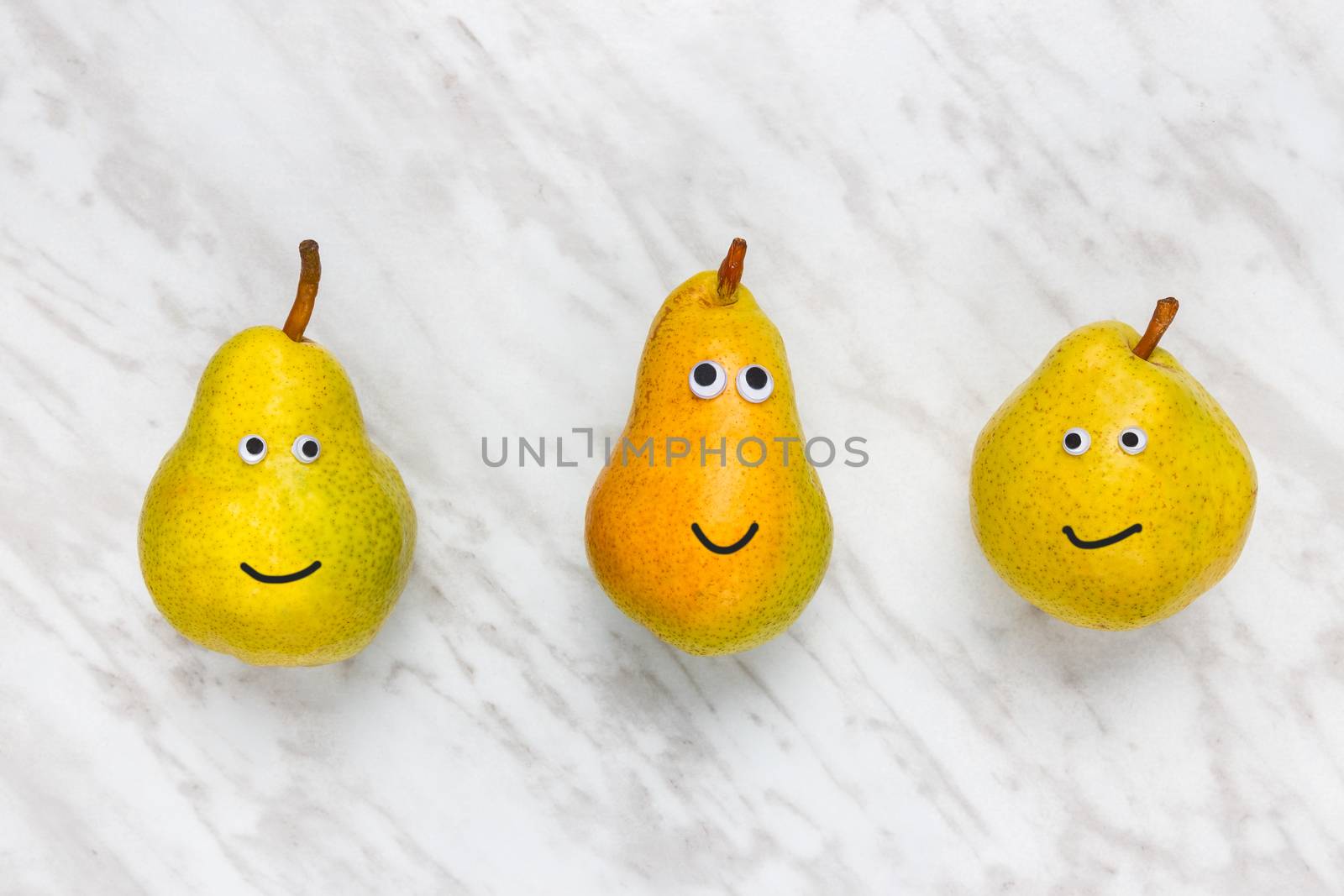 Three funny smiling pears on marble background. Different personalities.