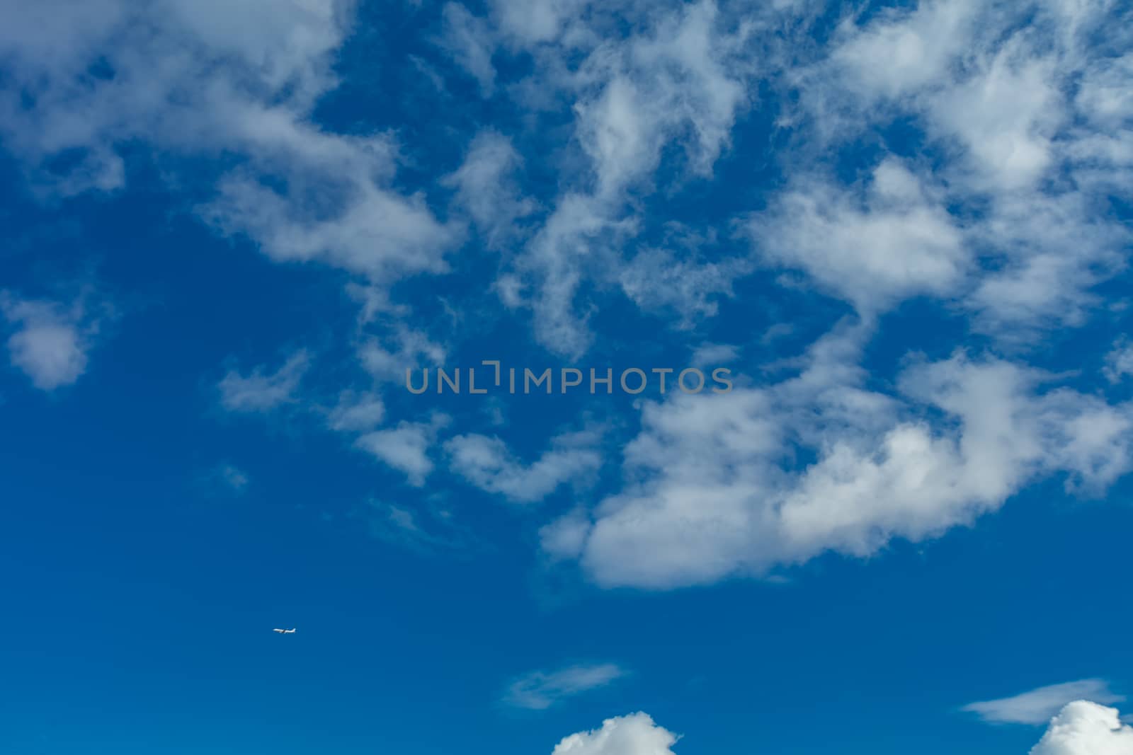 Deep blue bright sky with clouds  and plane